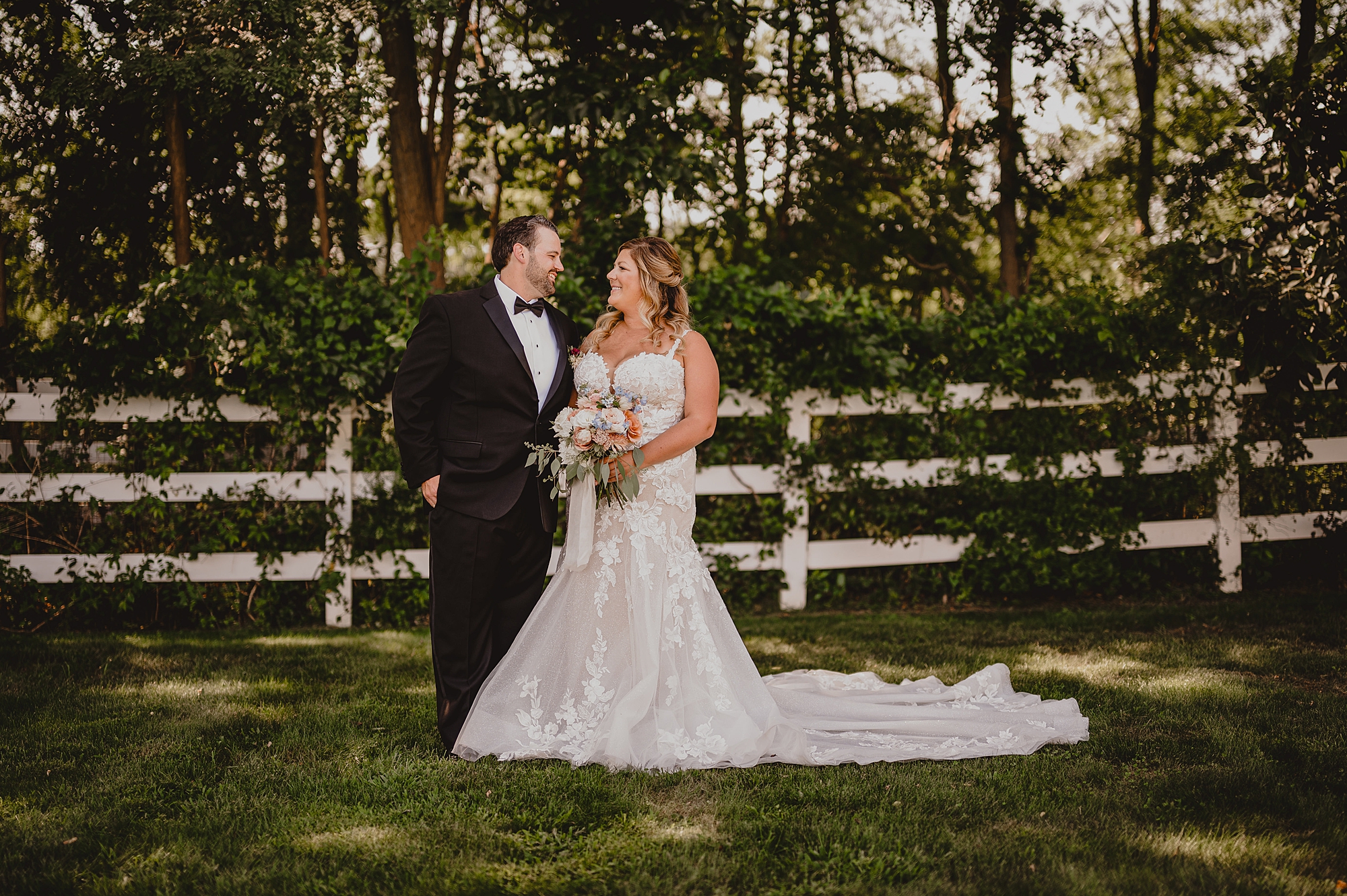 newlyweds hug by white wooden fence in New Jersey