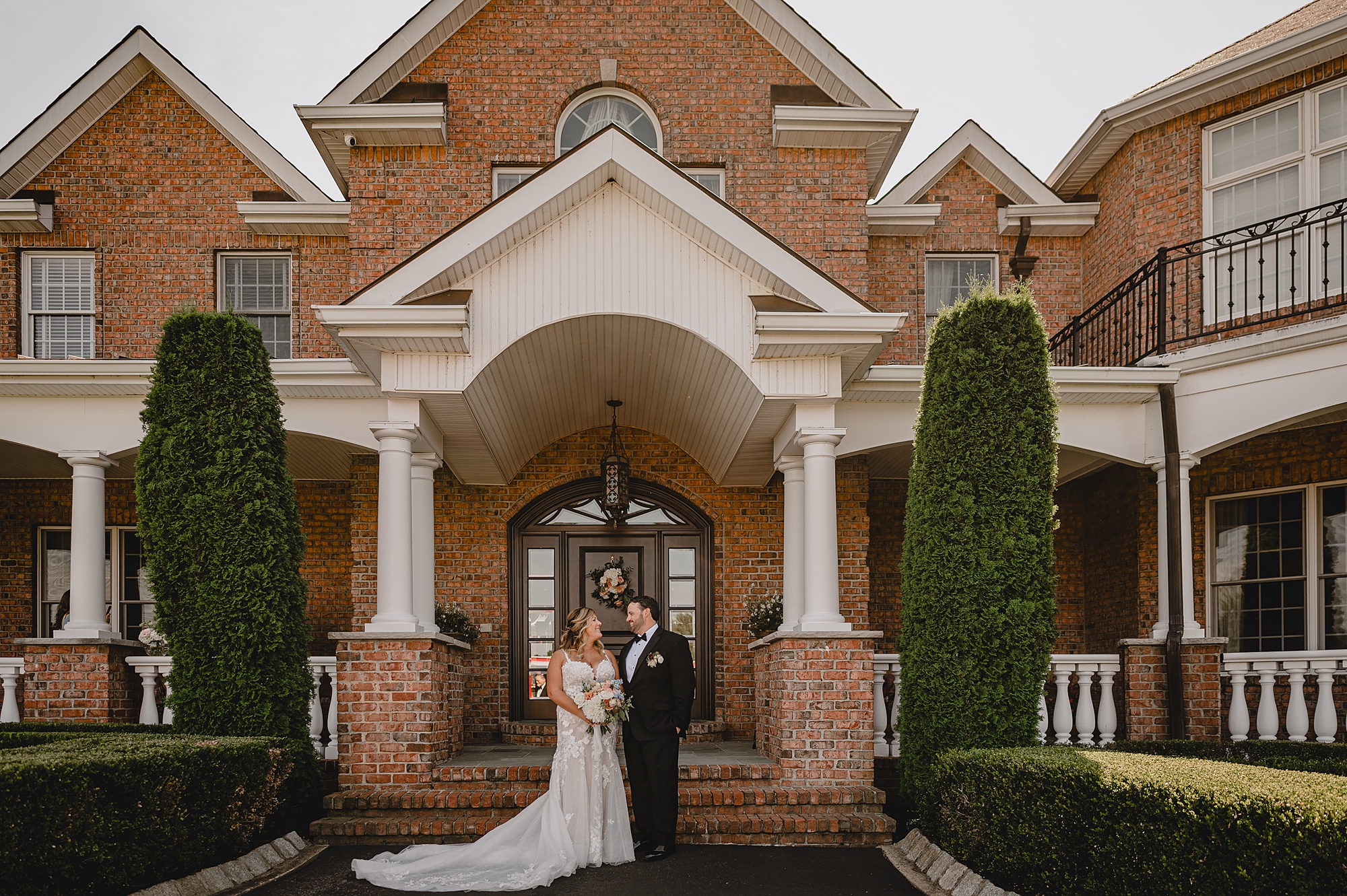 bride and groom stand in front of brick building at the Mill Lakeside Manor