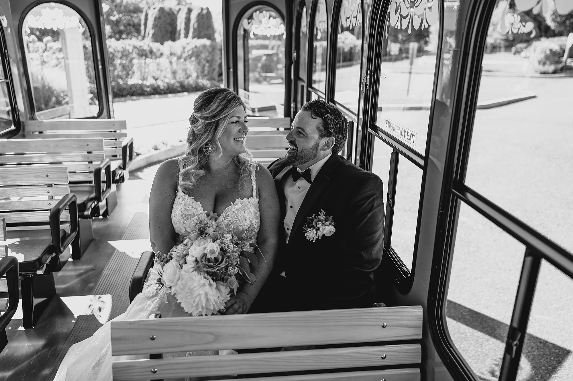 newlyweds sit on wooden bench on New Jersey trolley