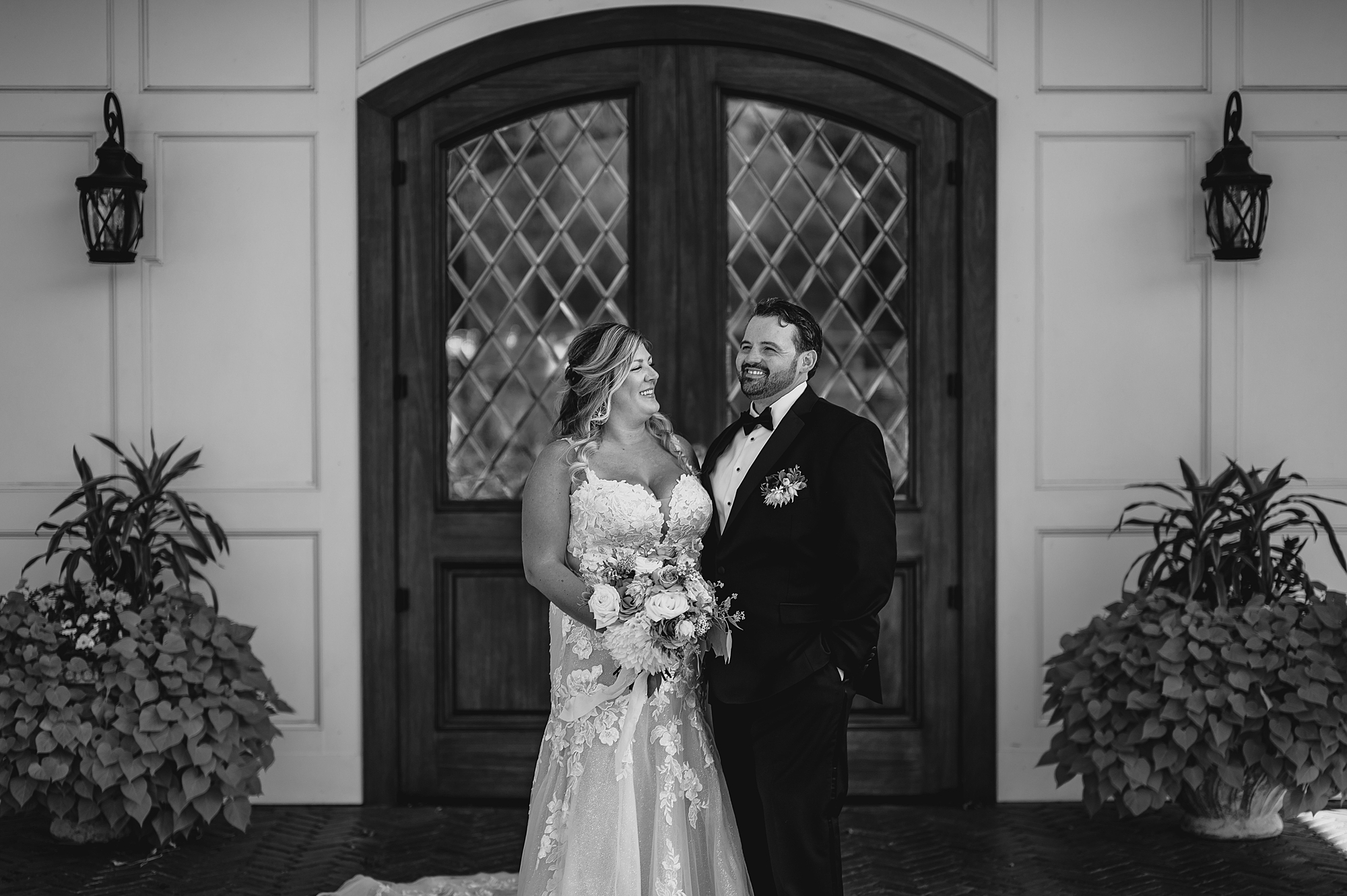 newlyweds laugh by wooden and glass doors at the Mill Lakeside Manor