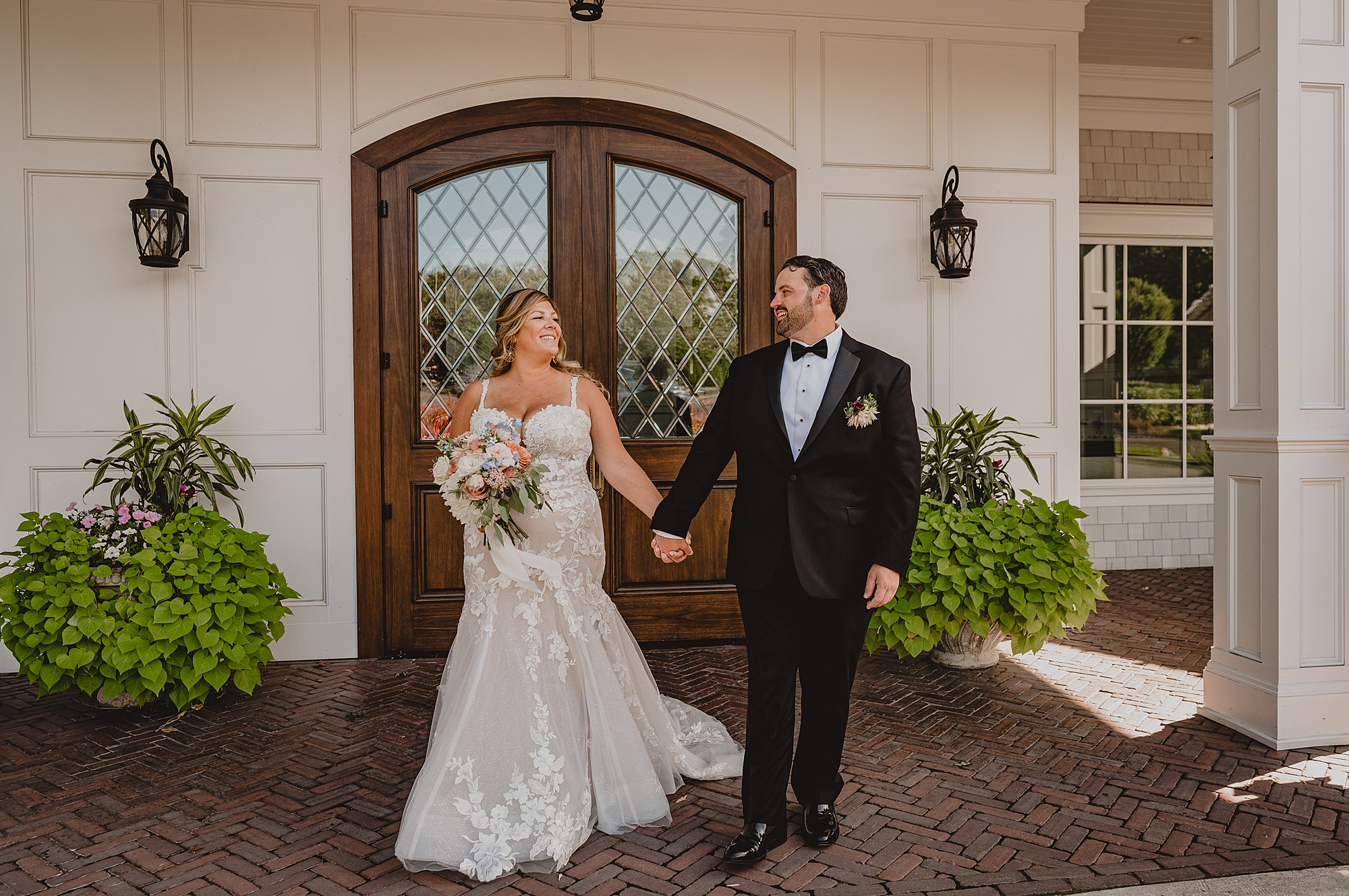 newlyweds hold hands walking away from wooden door at the Mill Lakeside Manor