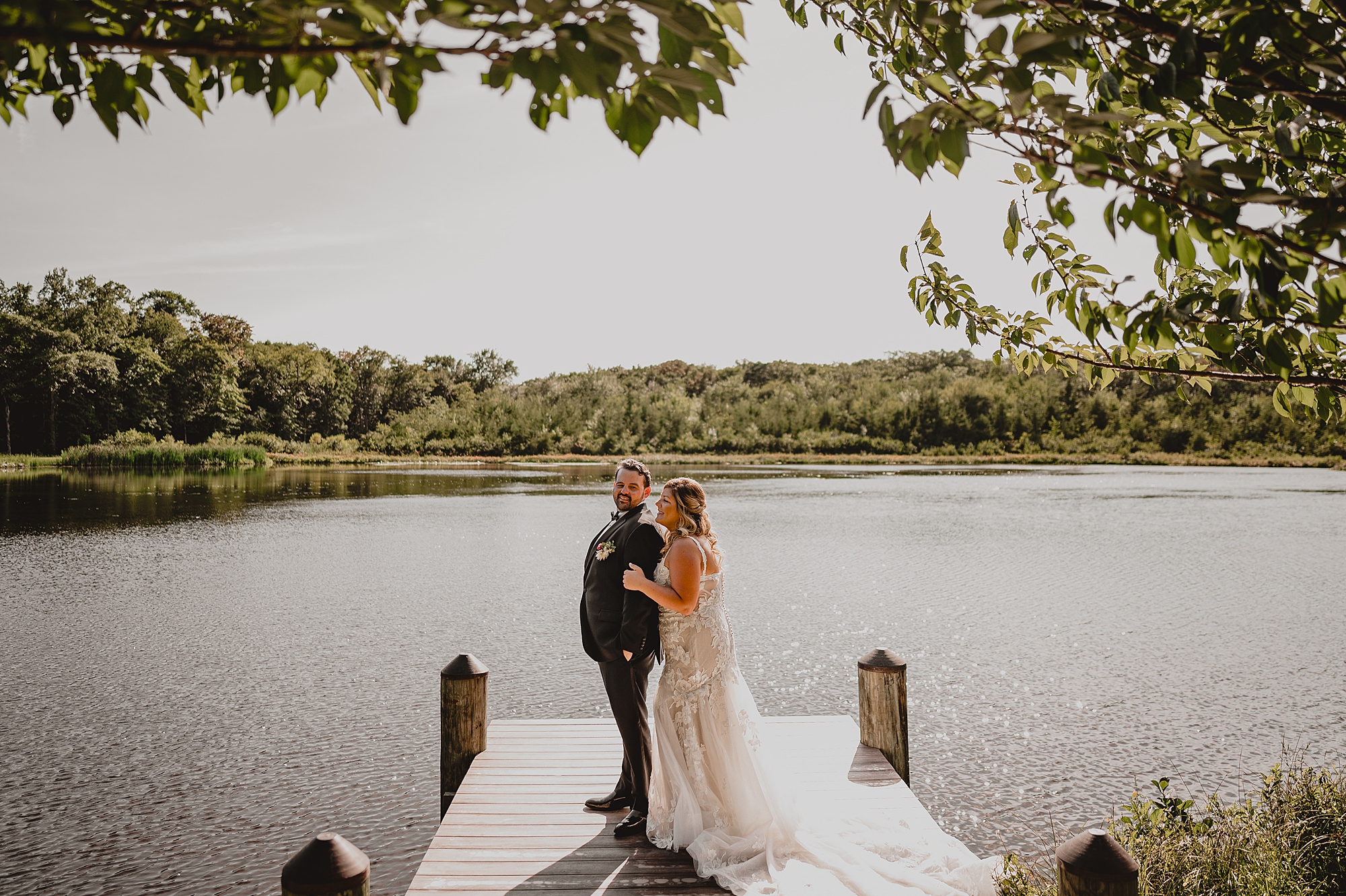 bride and groom stand on dock hugging at the Mill Lakeside Manor