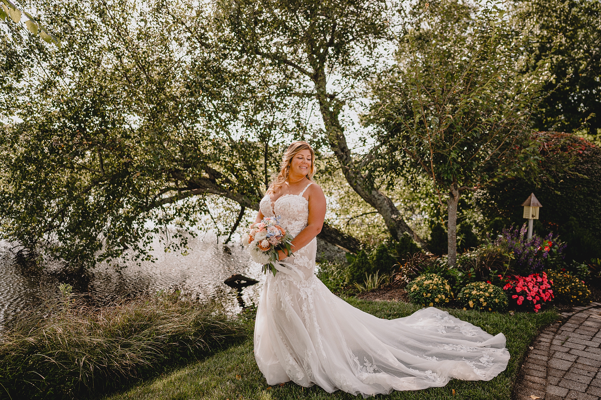 bride holds bouquet of fall flowers near tree