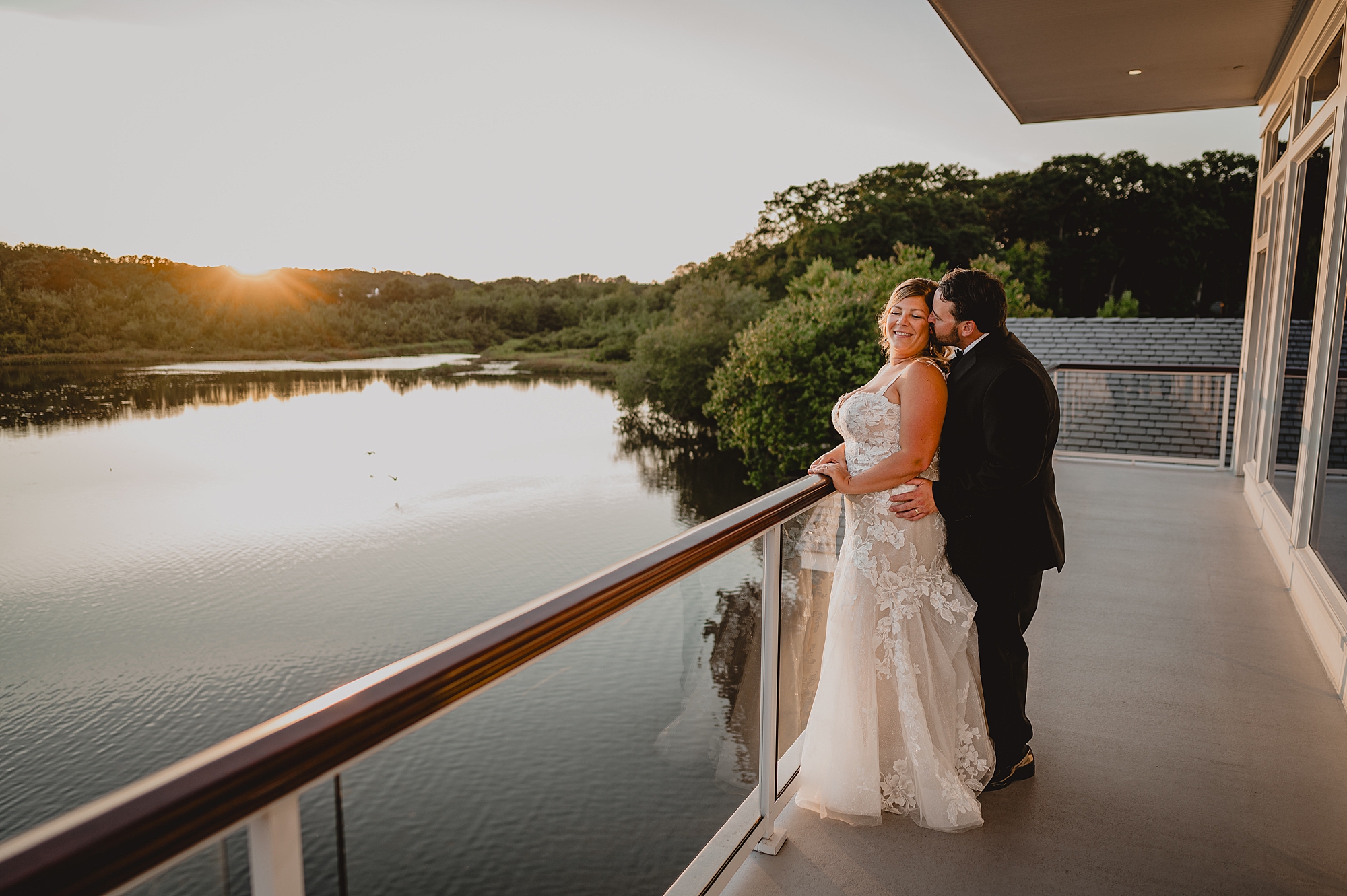 groom hugs bride from behind on balcony at the Mill Lakeside Manor