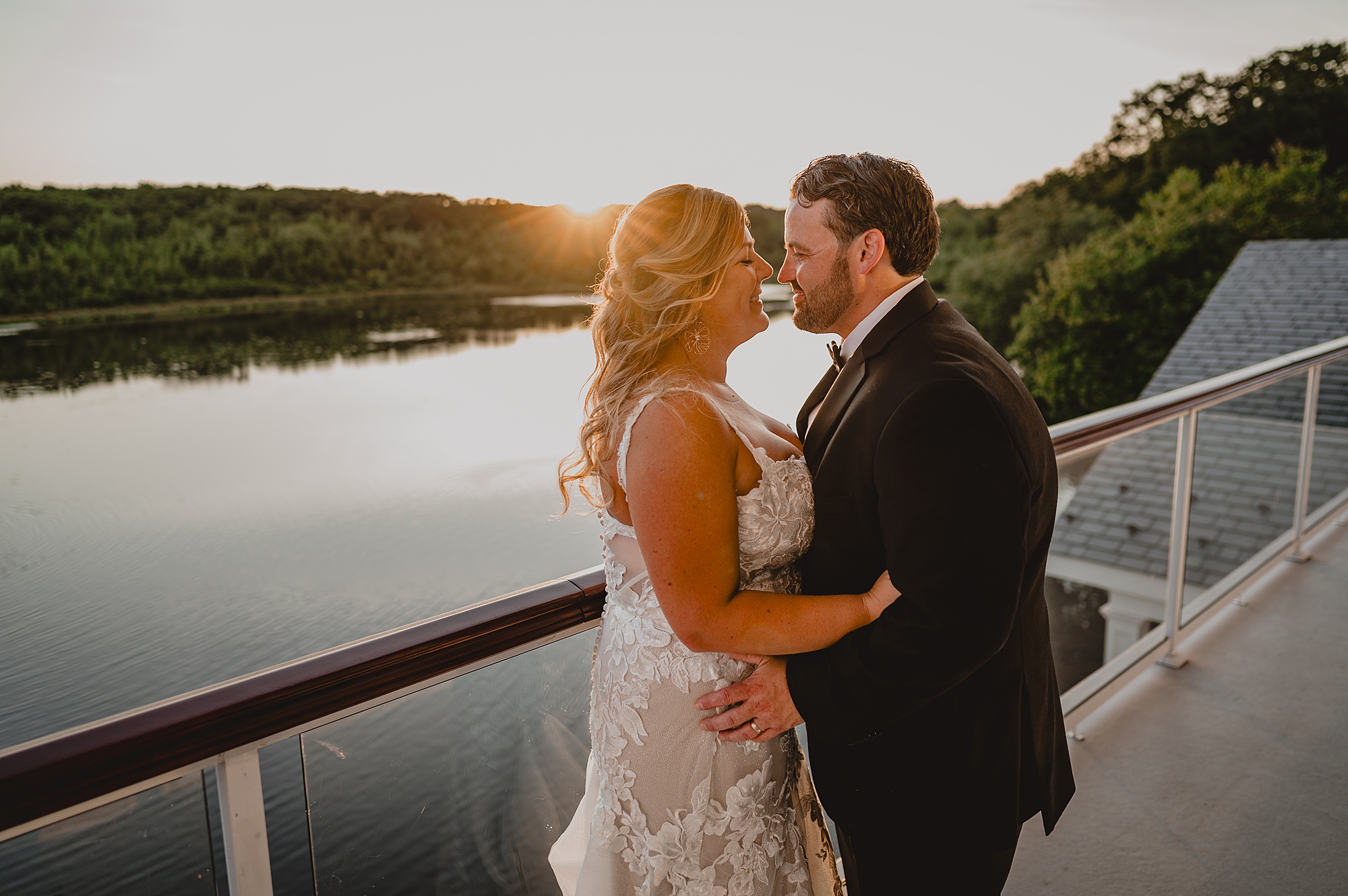 newlyweds lean to kiss on balcony at the Mill Lakeside Manor