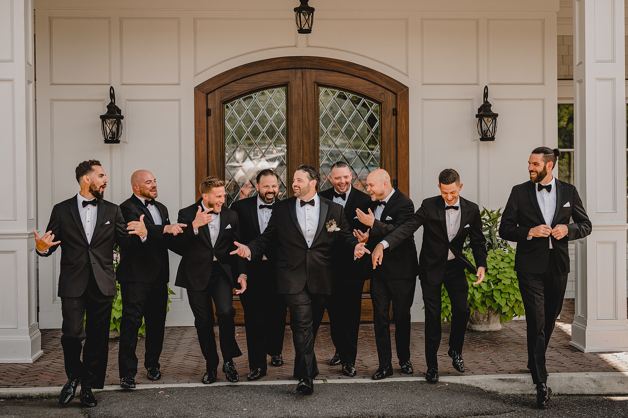 groom walks with groomsmen outside the Mill Lakeside Manor
