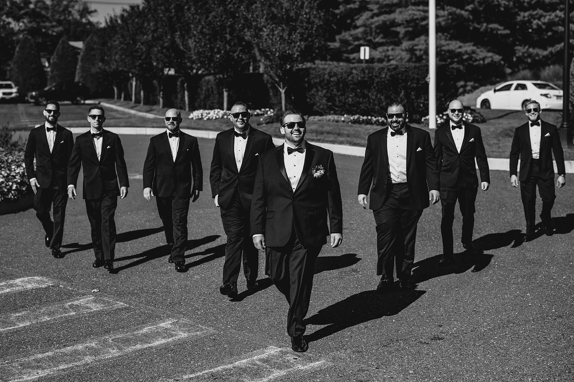 groom walks through parking lot with groomsmen
