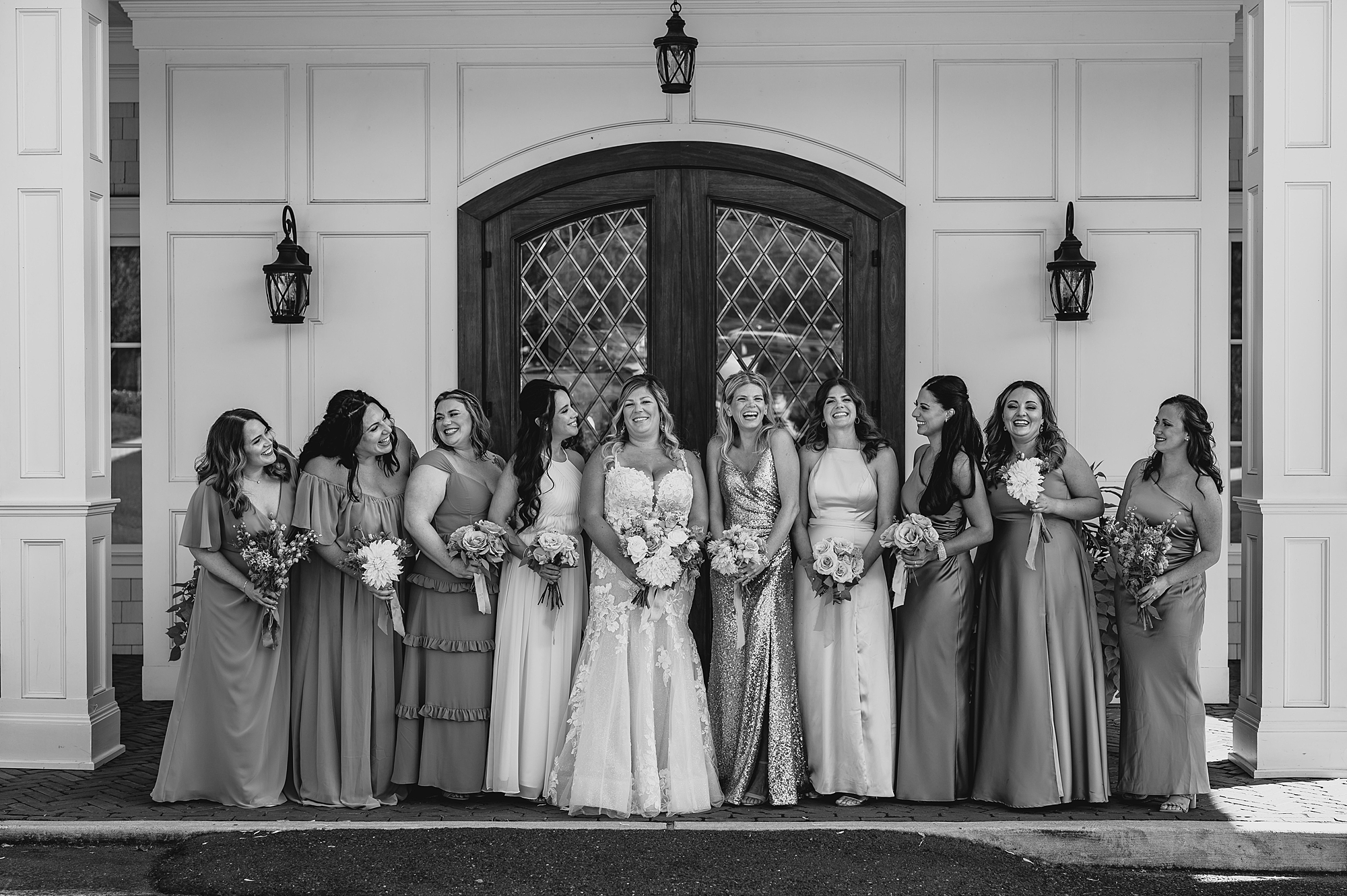 bride stands with bridesmaids in mismatched gowns outside the Mill Lakeside Manor