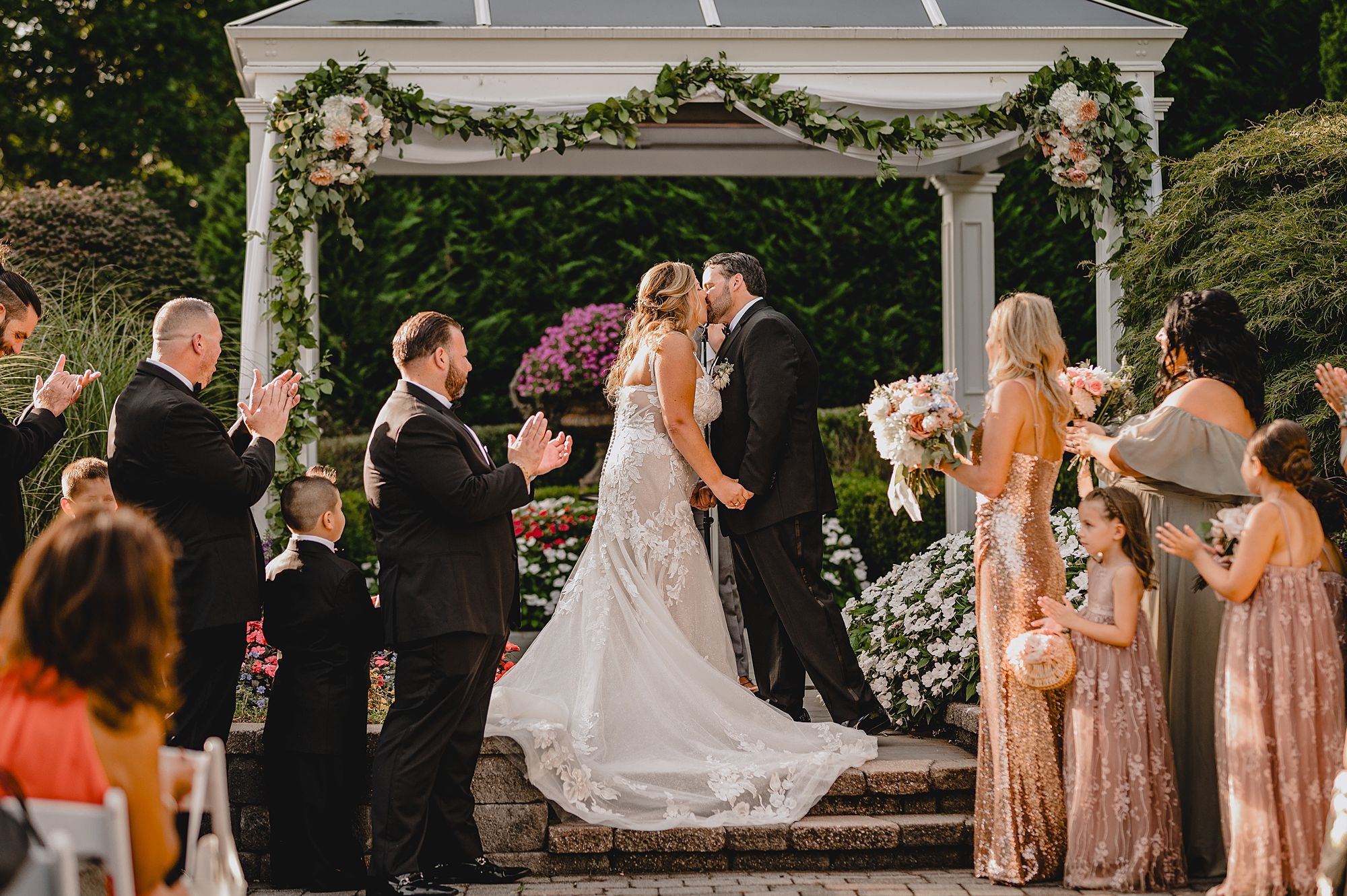 newlyweds kiss under arbor at the Mill Lakeside Manor