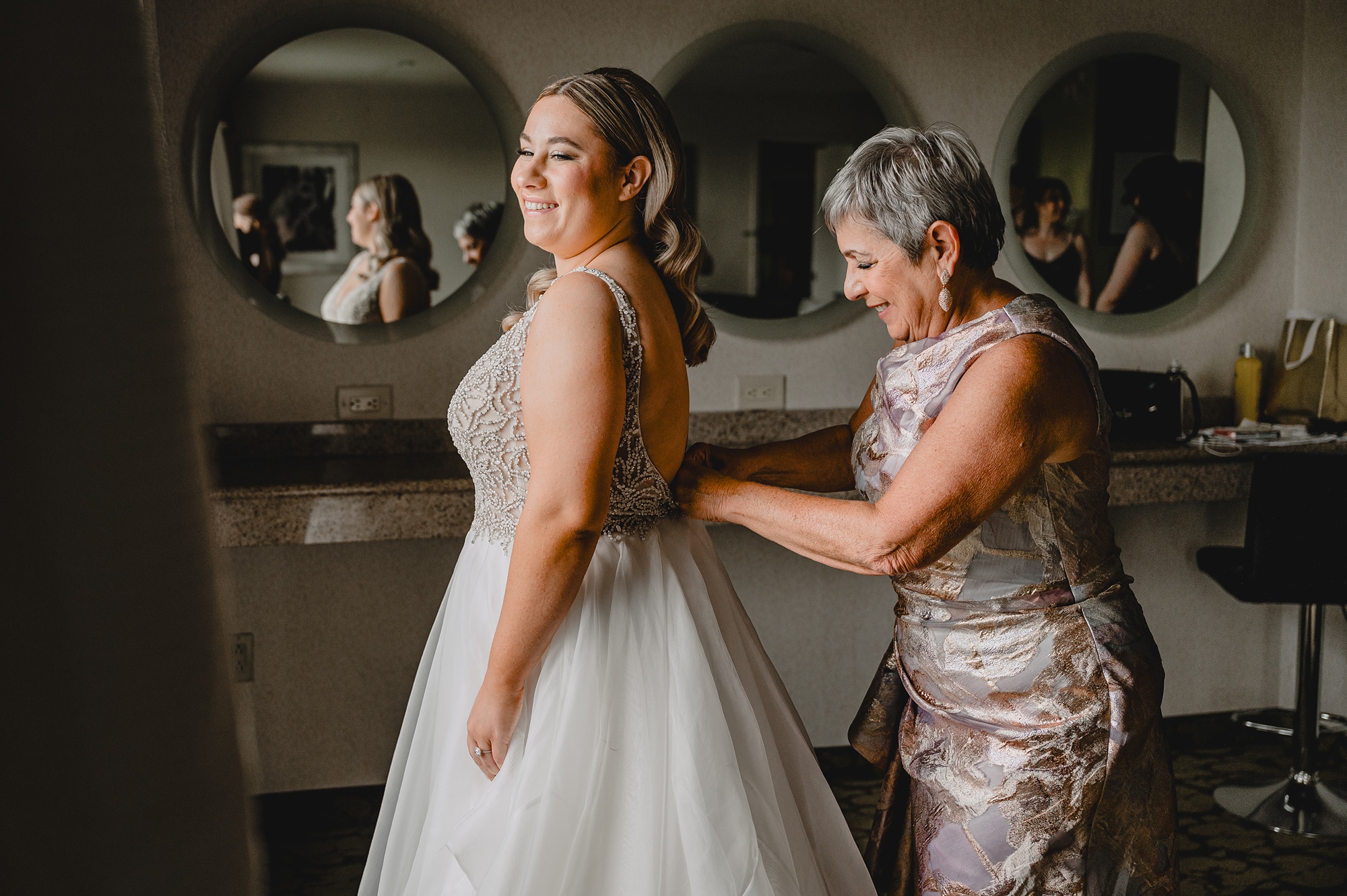 mother helps bride into wedding dress in Staten Island hotel