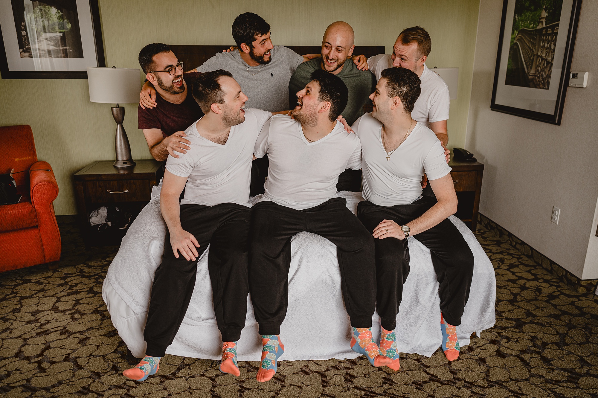 groom sits with groomsmen in white t-shirts and black sweatpants