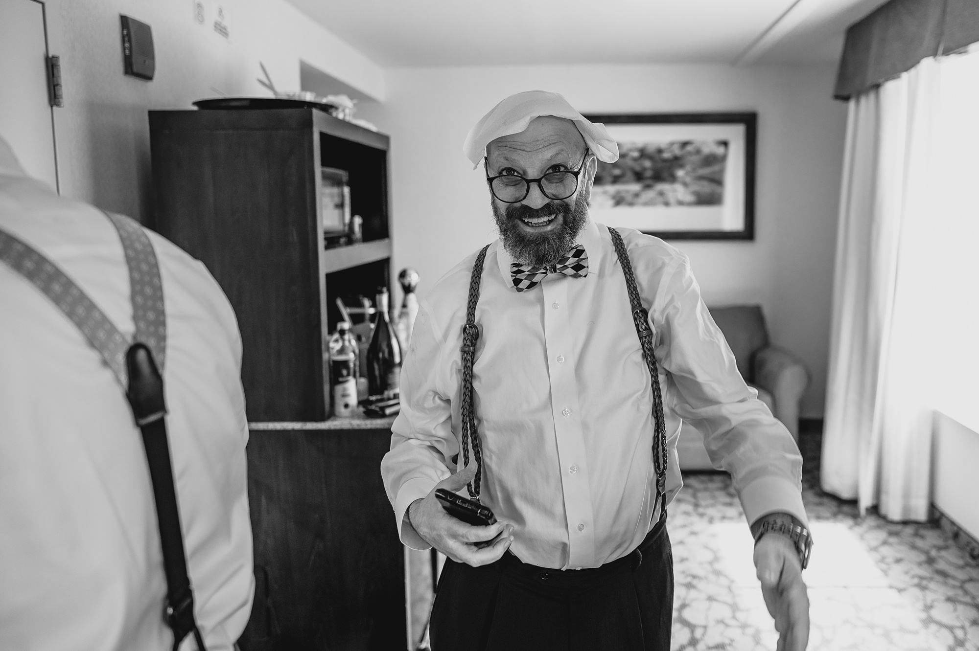 groom walks through hotel room with washcloth on his head