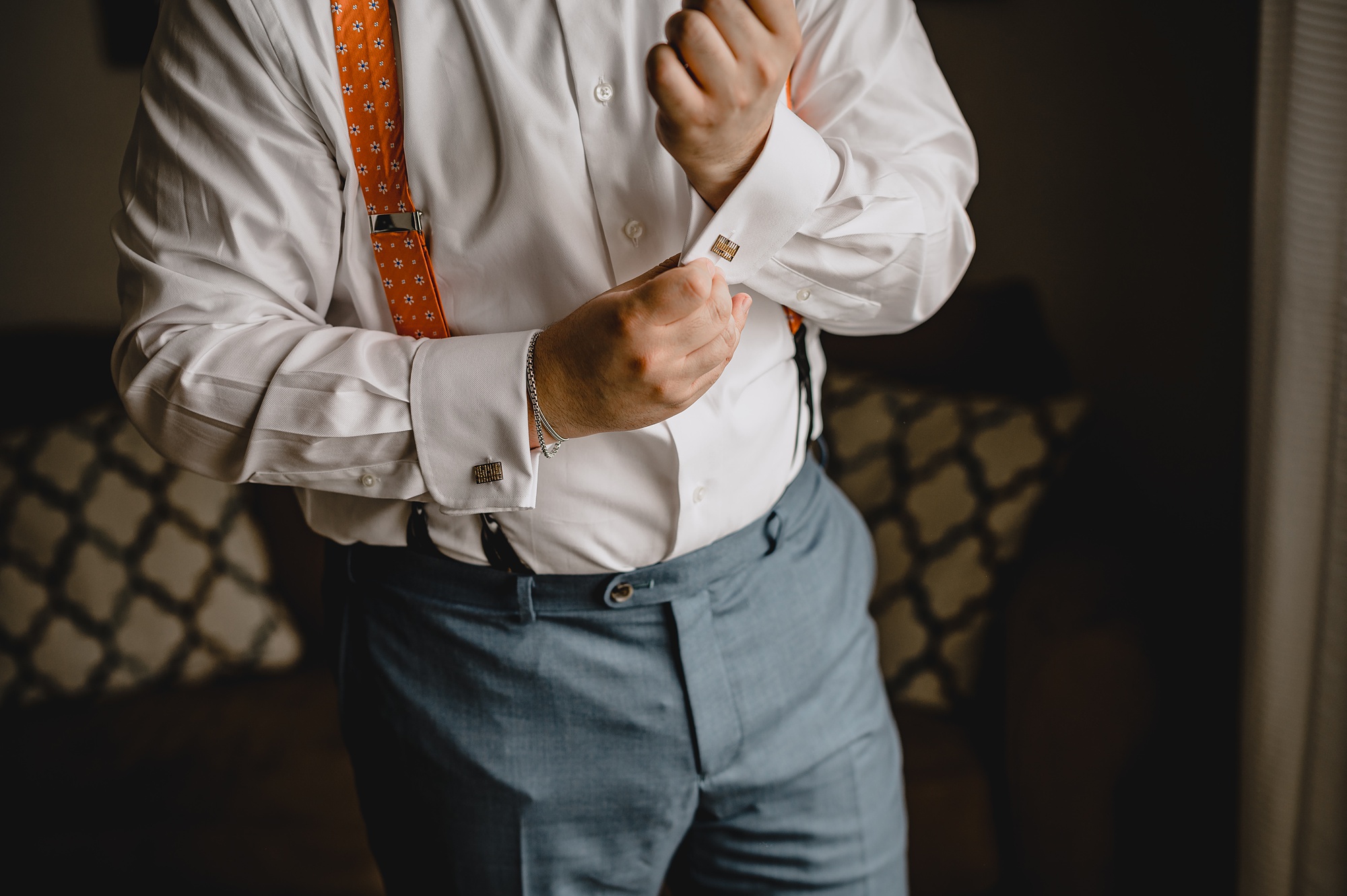 groom adjusts cufflinks during prep in Staten Island hotel