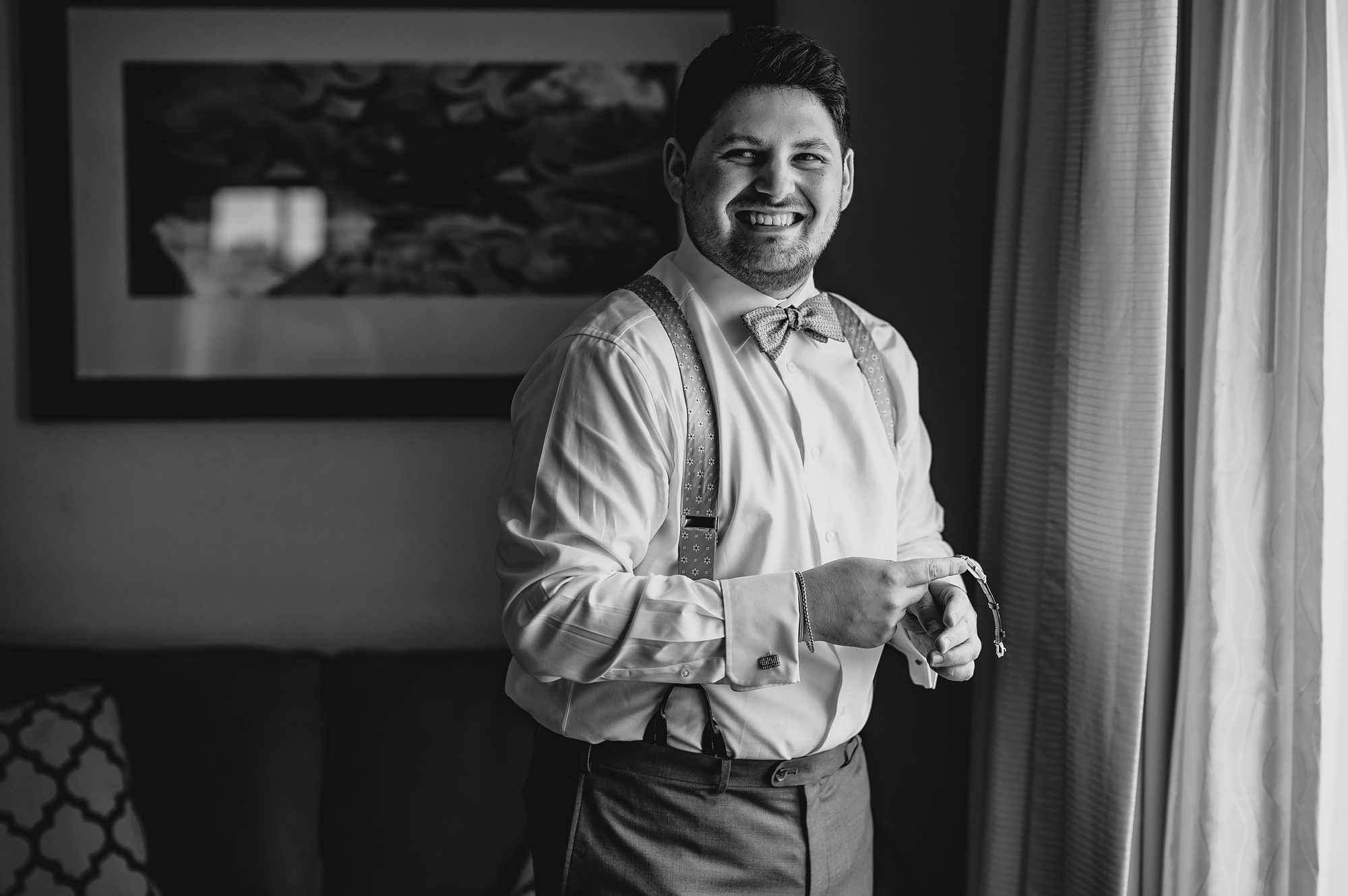 man laughs by window of hotel room