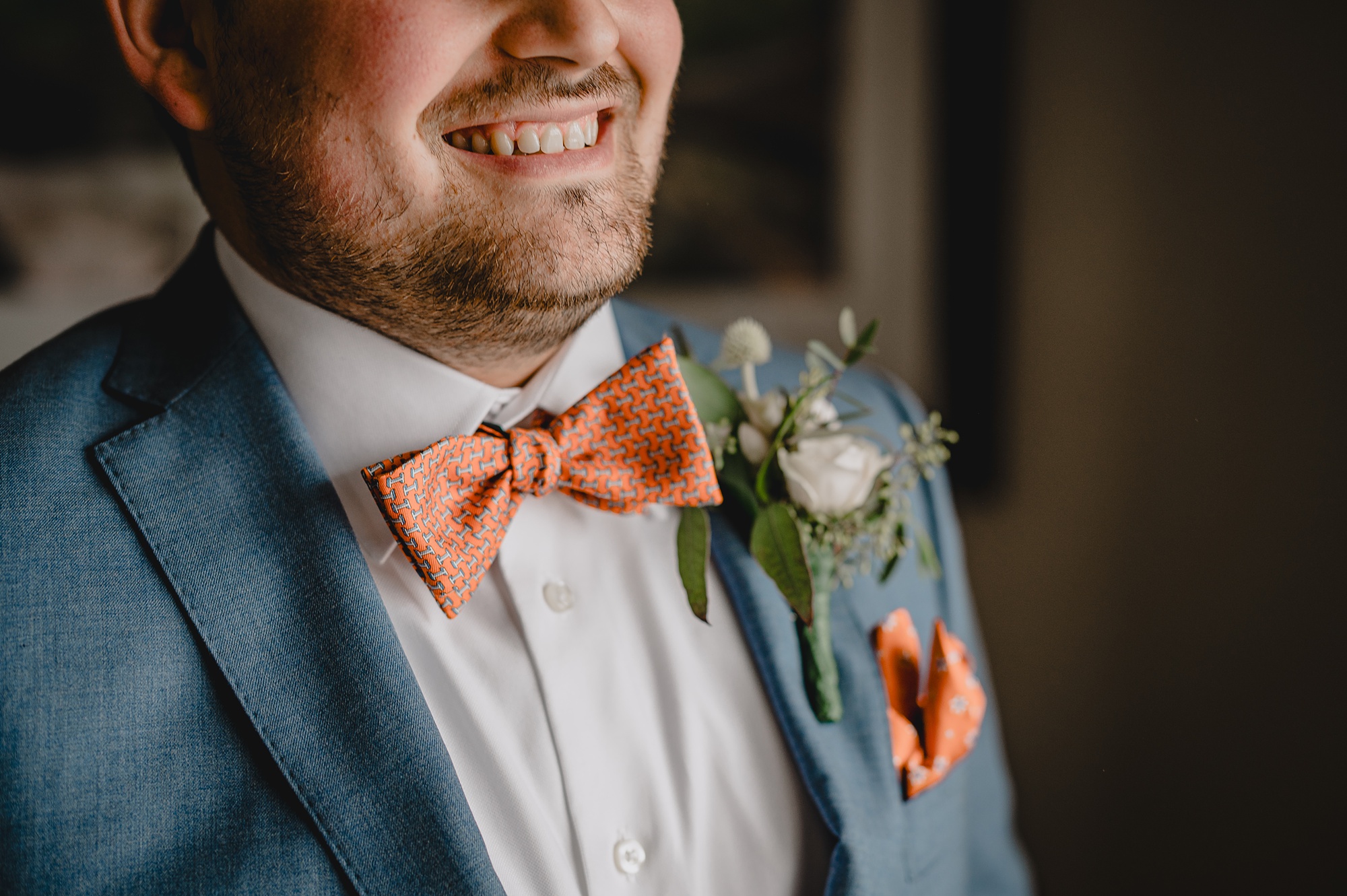 man in blue suit with burnt orange bowtie and pocket square