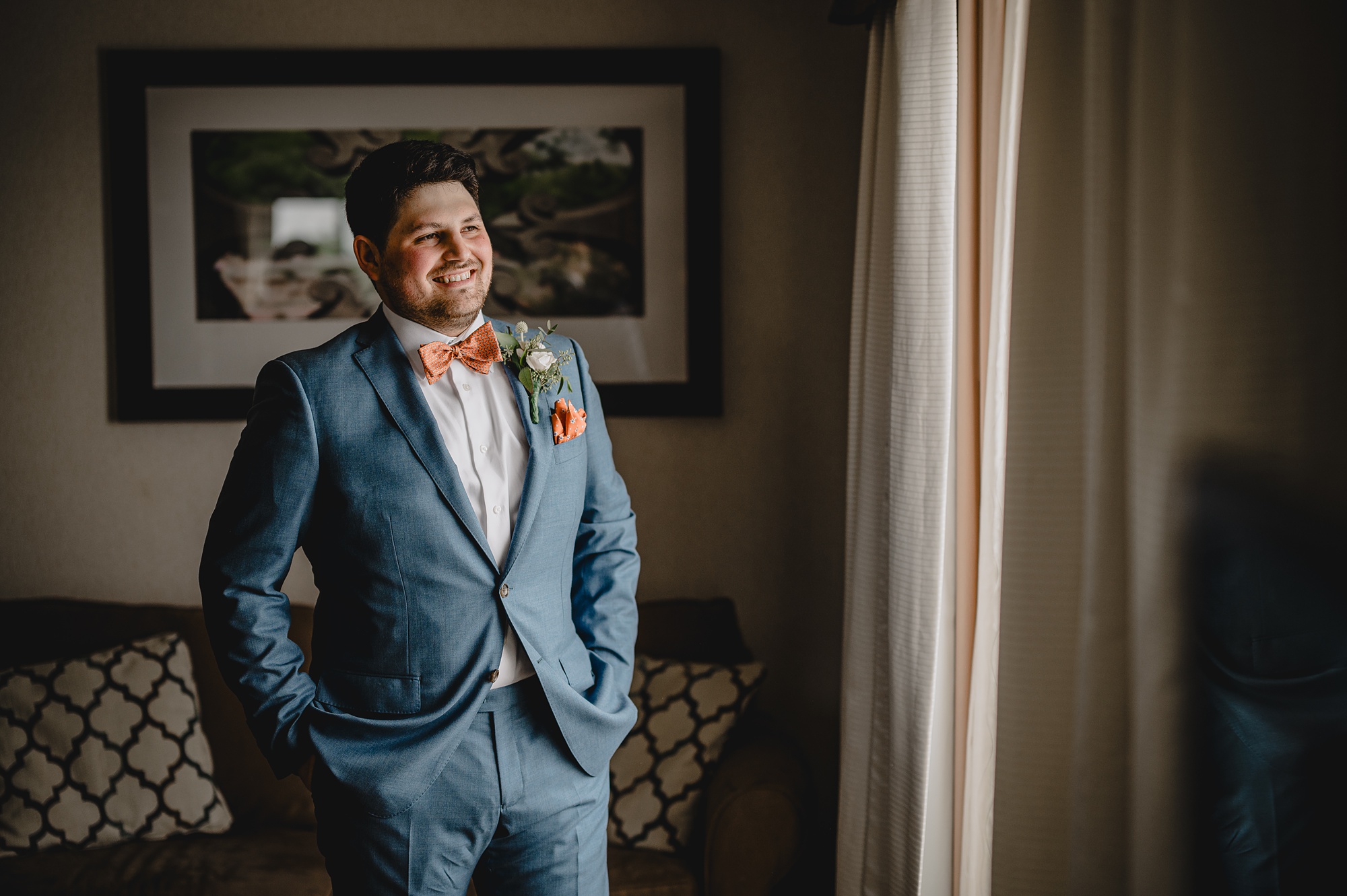 man in blue suit with orange bow tie and pocket square during prep at Staten Island hotel