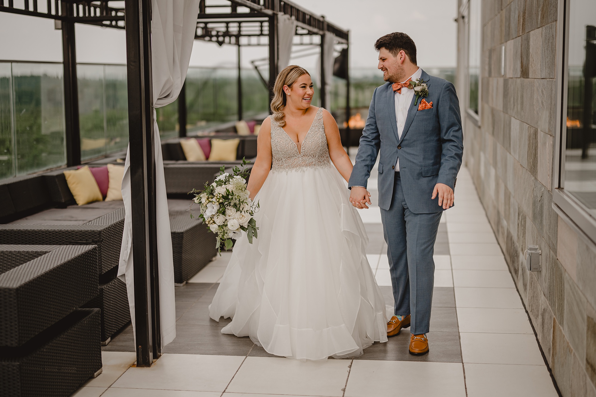 bride and groom hold hands walking across patio rooftop at Above Staten Island