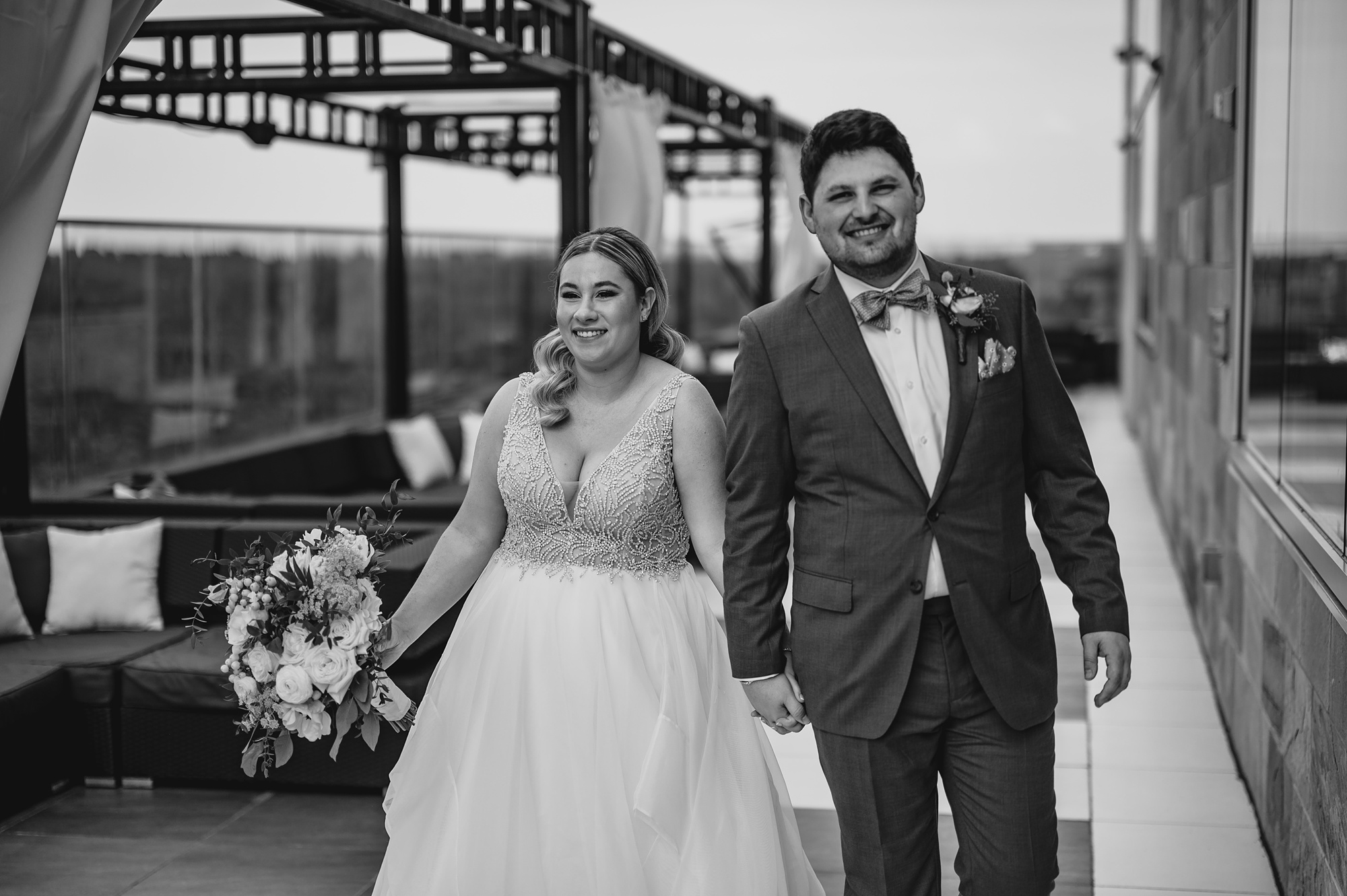 newlyweds hold hands laughing walking across patio at Above Staten Island