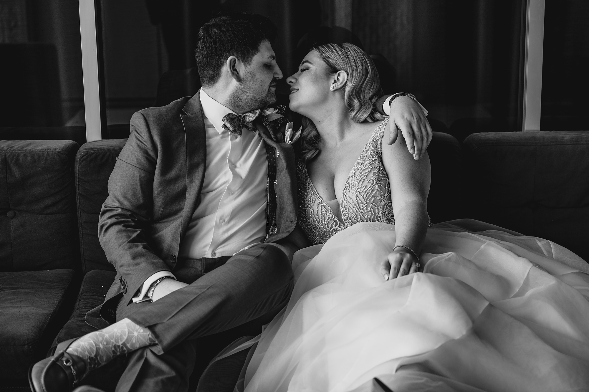 newlyweds kiss on sofa during portraits at Above Staten Island