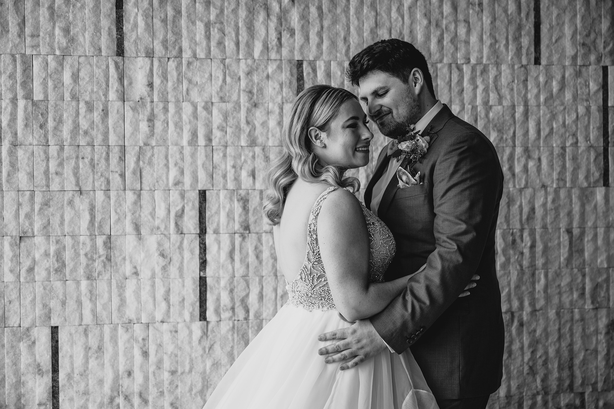 bride and groom hug in front of wall at Above Staten Island