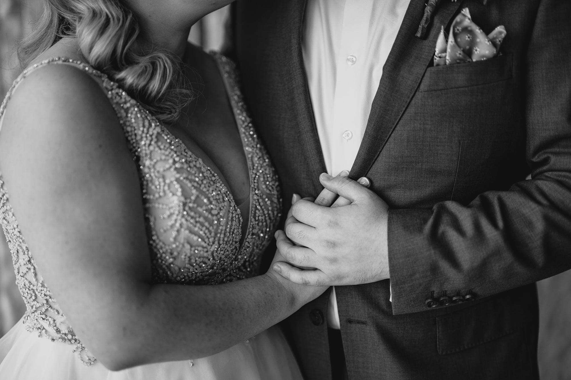 bride and groom hold hands in front of his suit jacket 