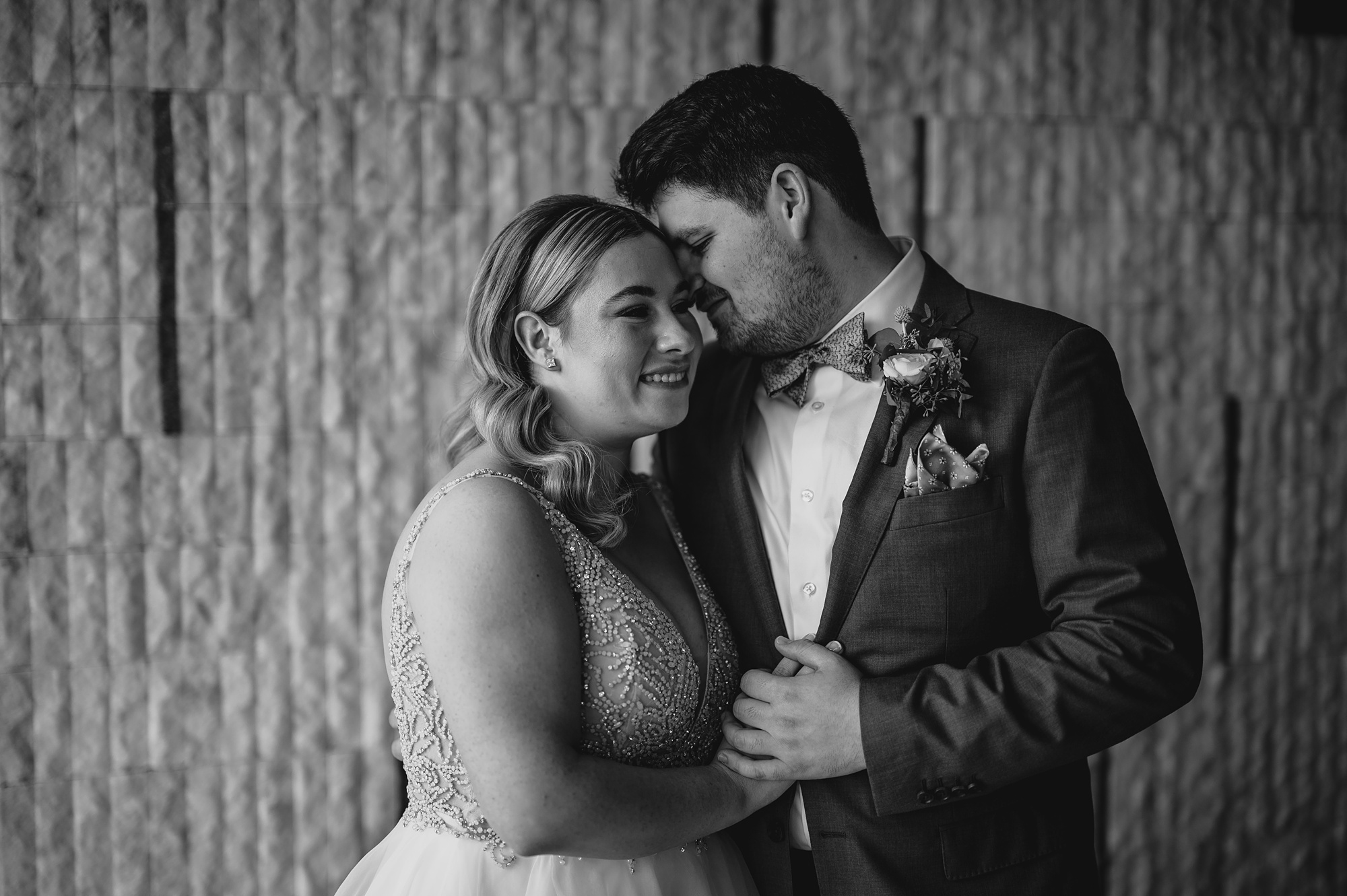 black and white photo of bride and groom hugging by wall at Above Staten Island