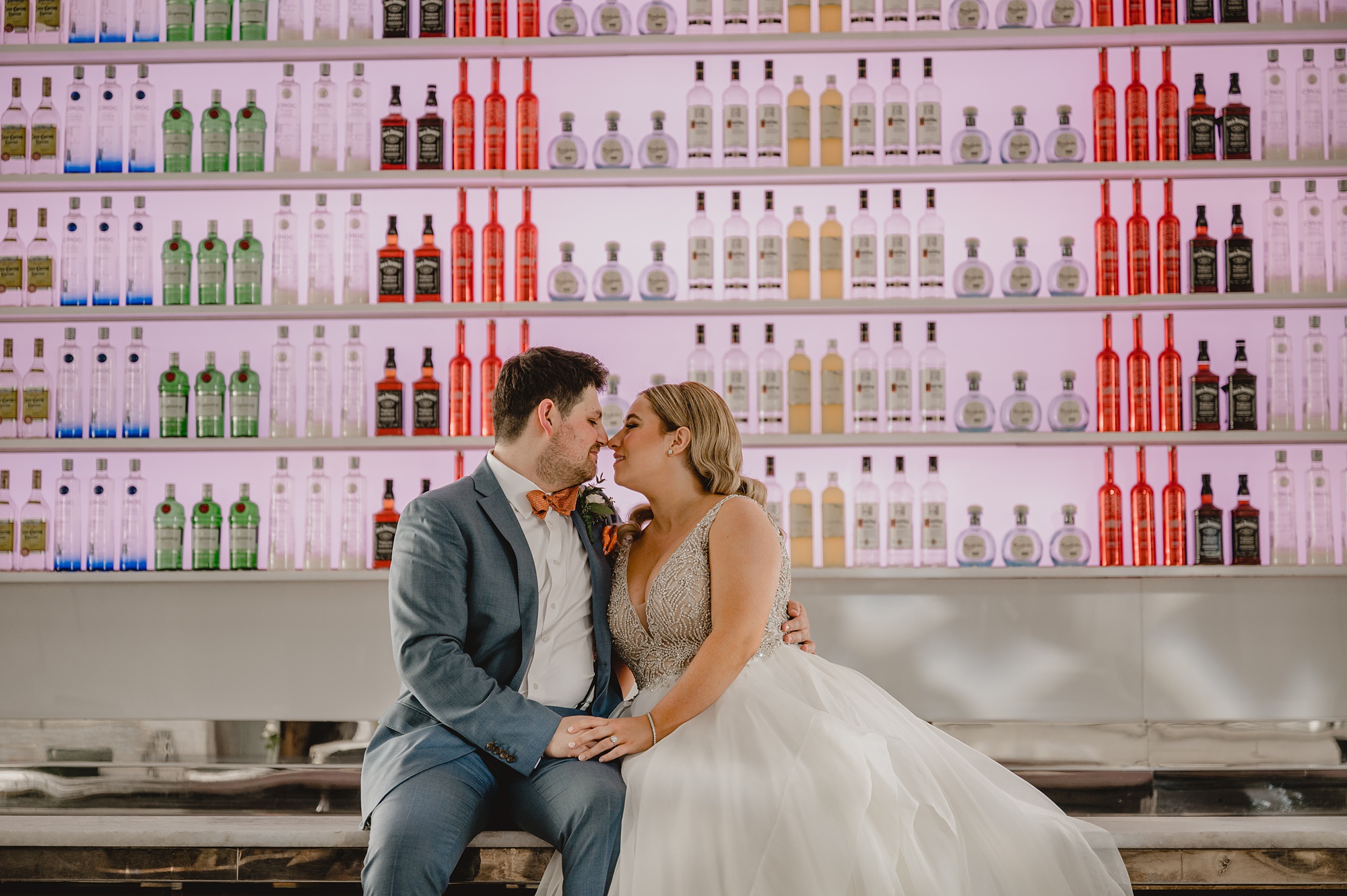 bride and groom sit on bar kissing inside Above Staten Island