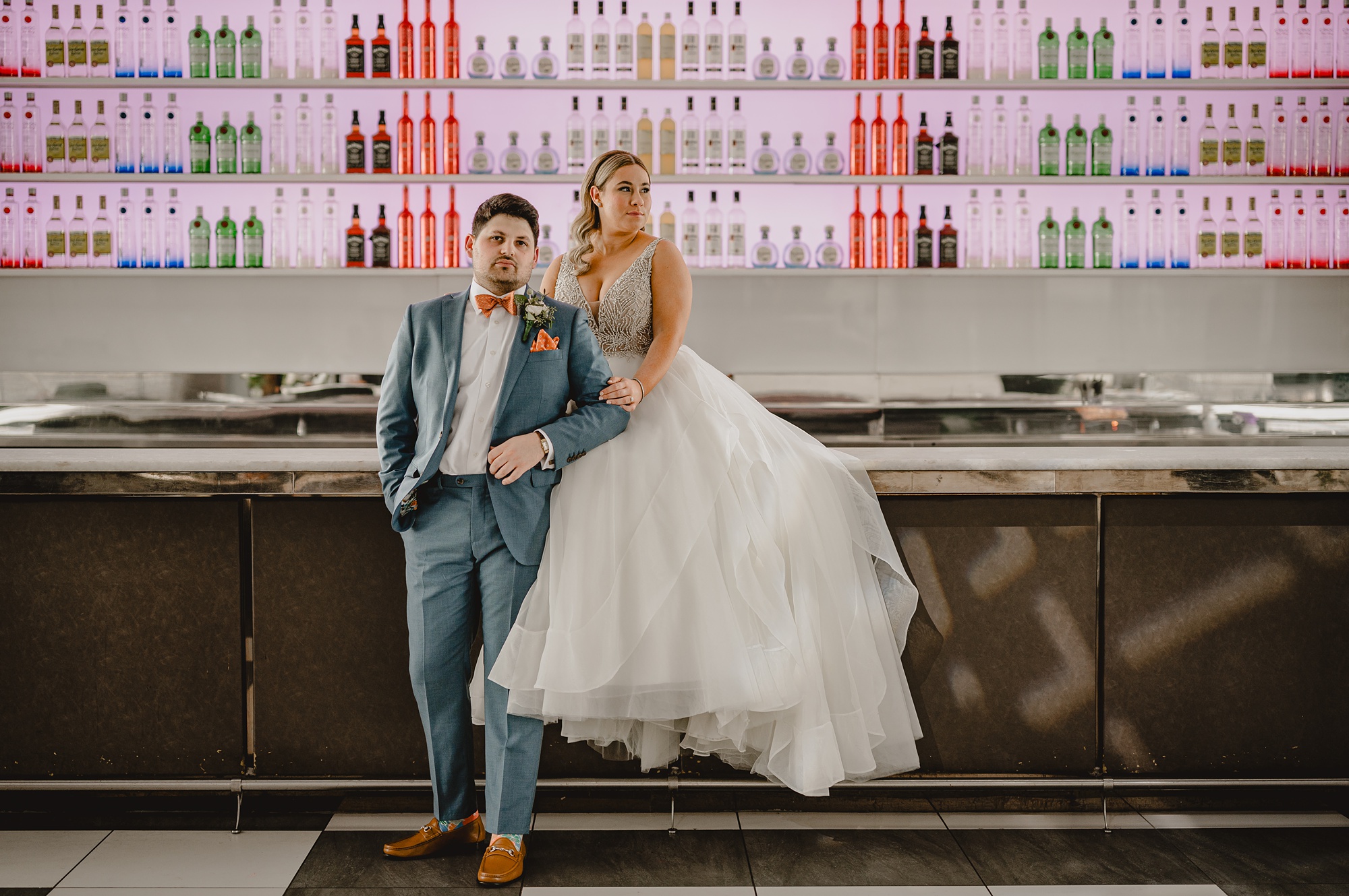 bride and groom sit on bar inside Above Staten Island