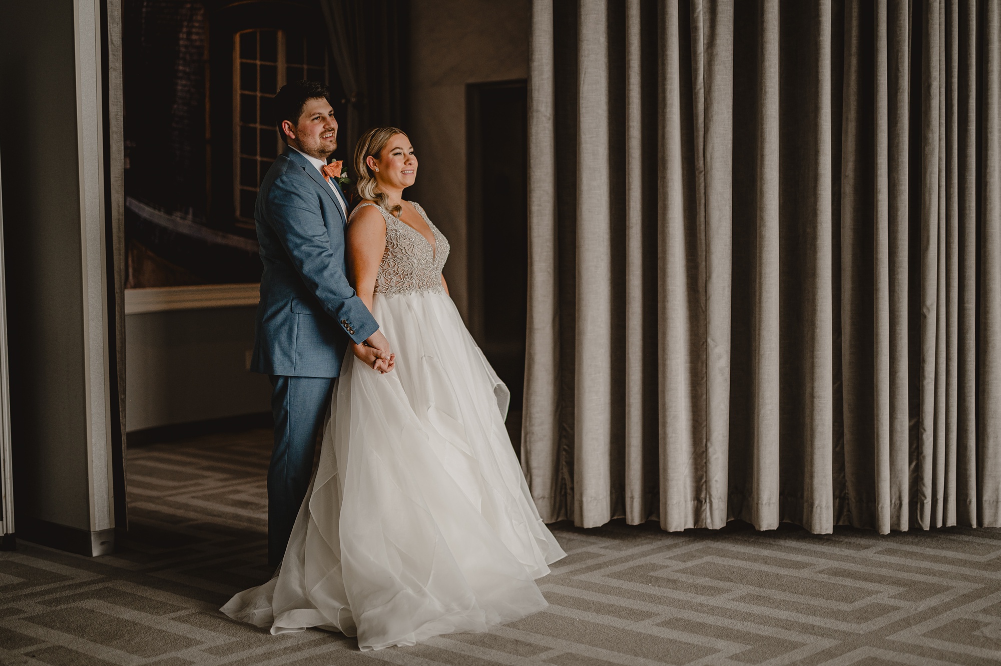 bride and groom hug in front of wall at Above Staten Island