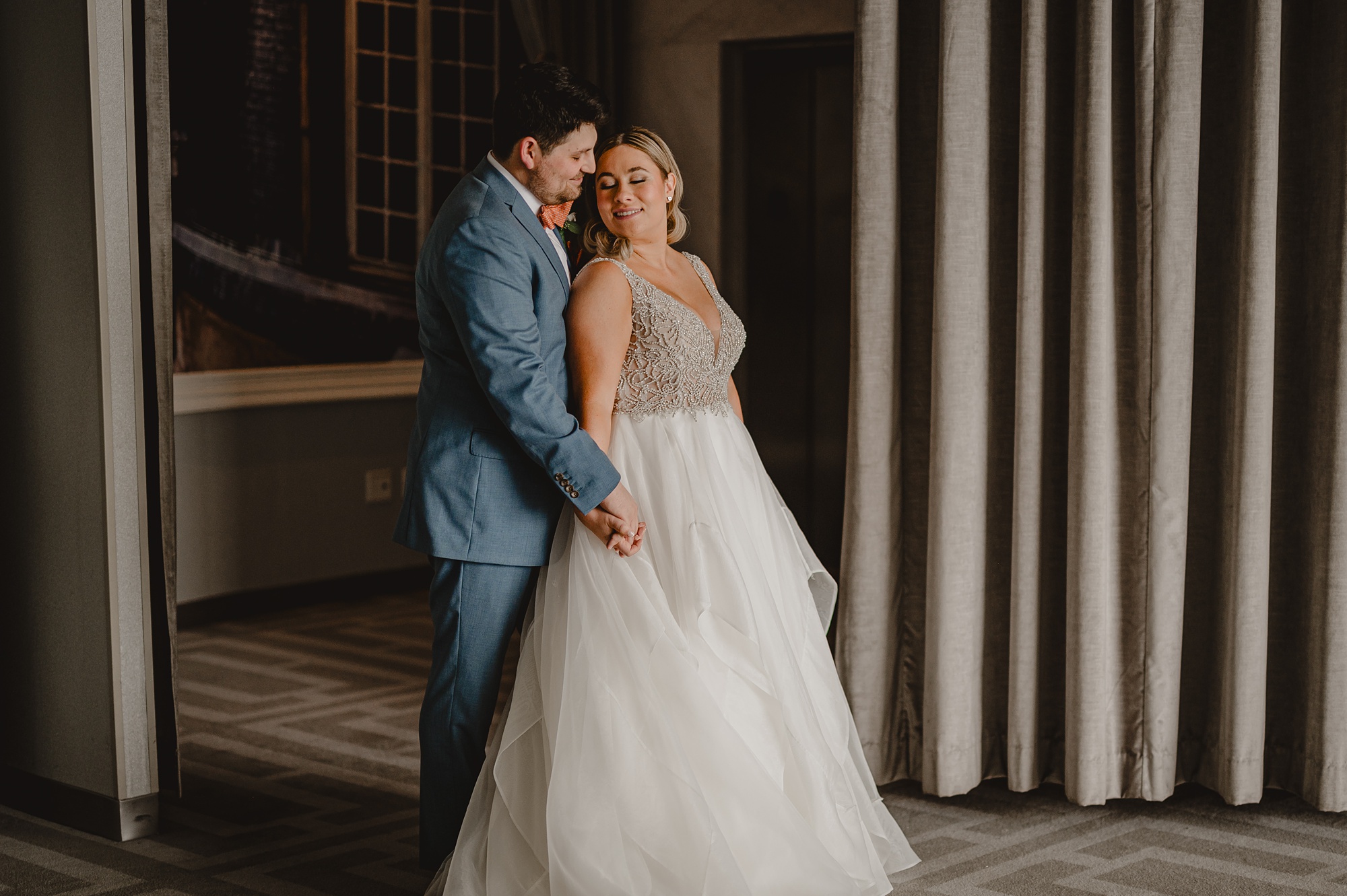 newlyweds hug in front of grey wall at Above Staten Island
