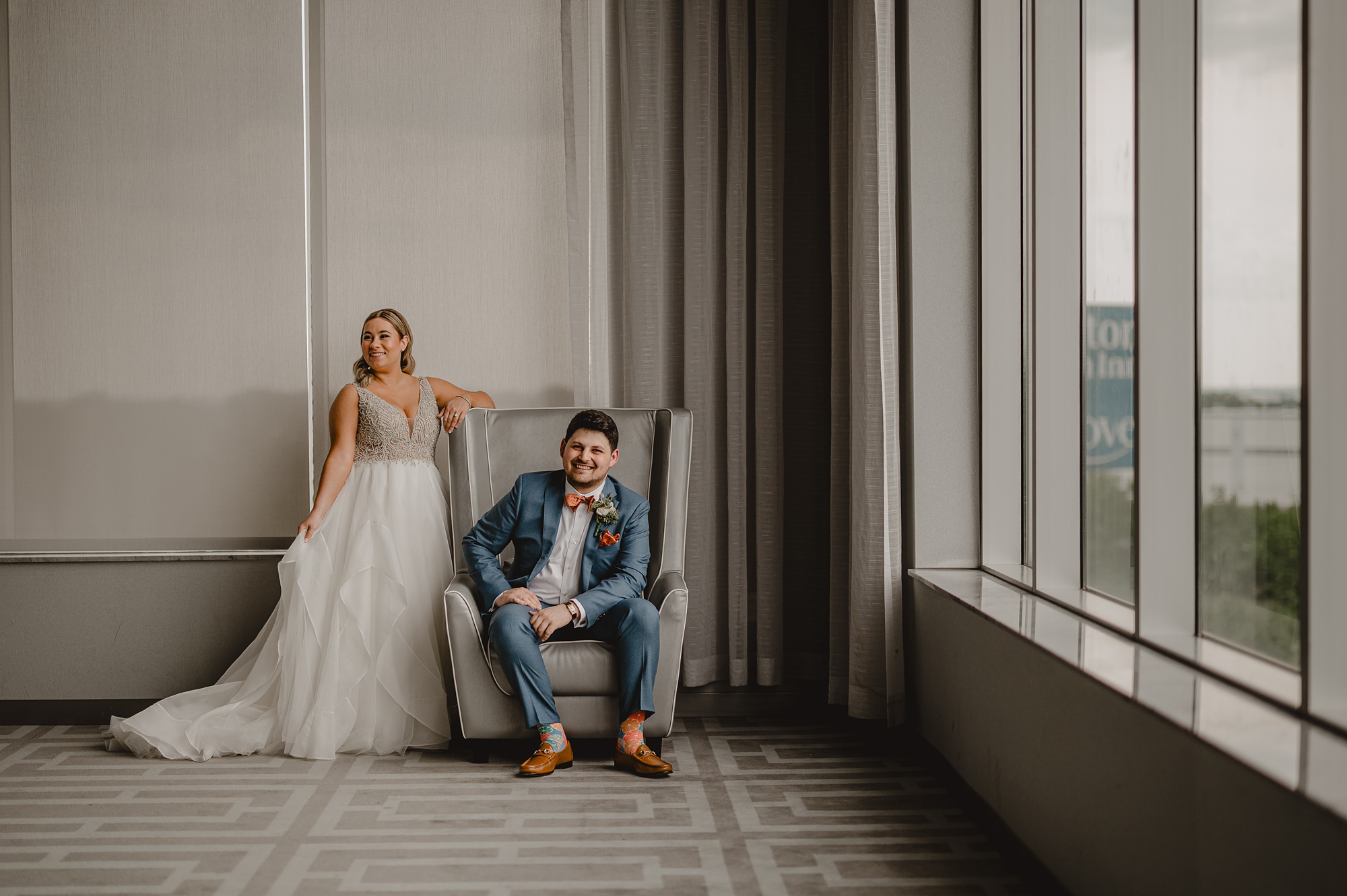 groom sits in chair while bride leans against his chair at Above Staten Island
