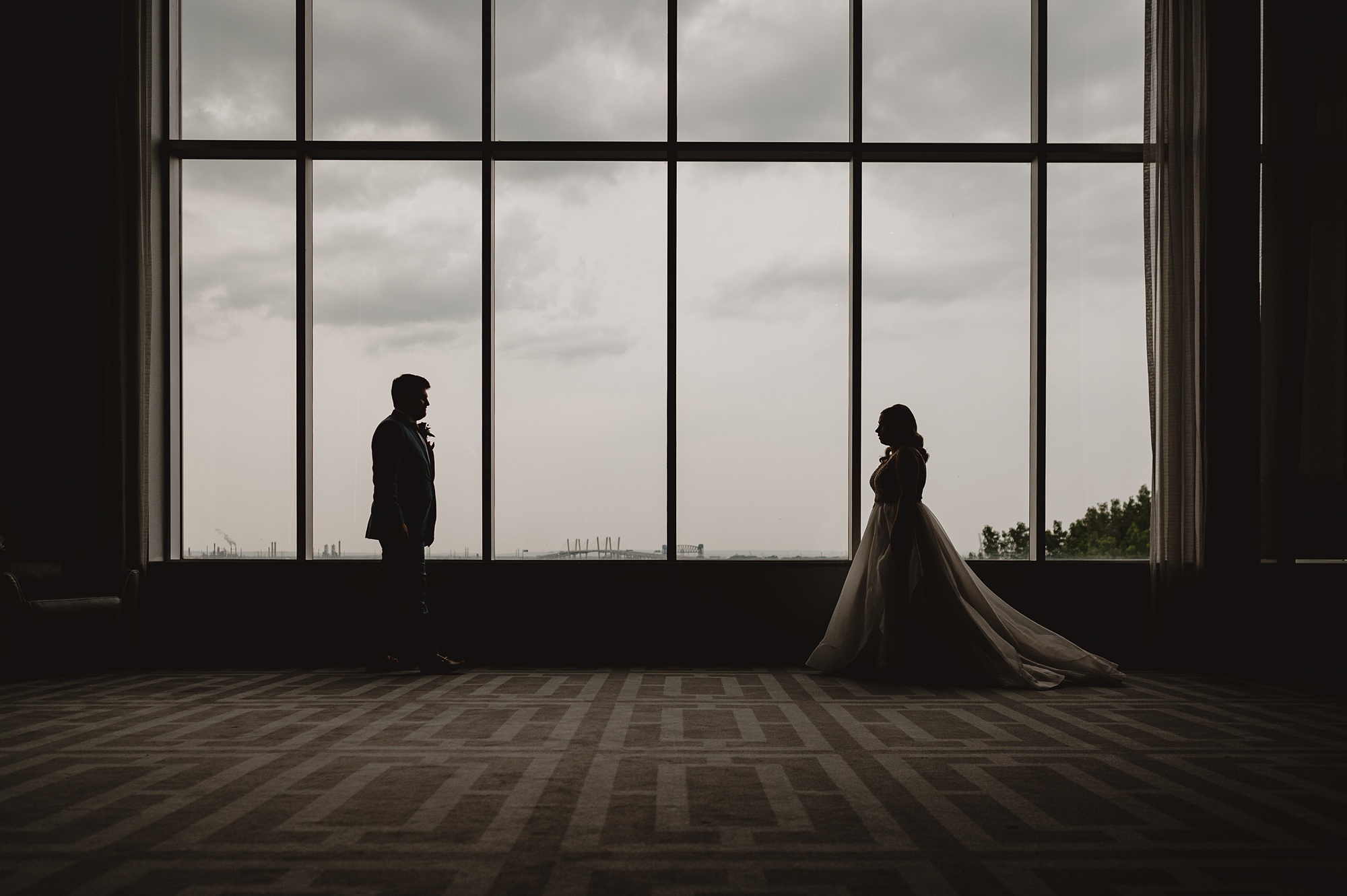 newlyweds stand apart in front of glass window at Above Staten Island