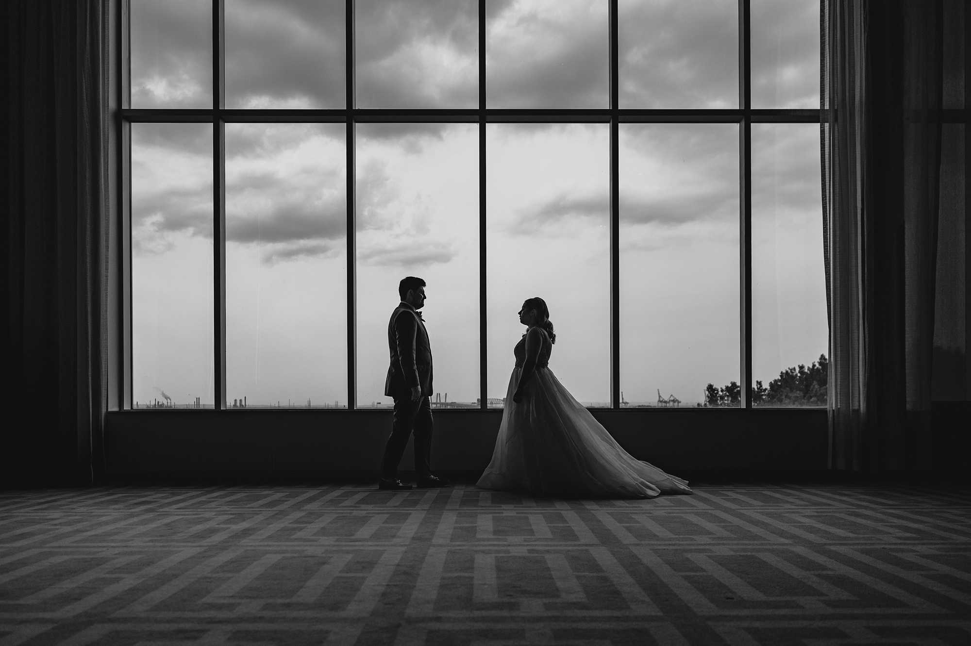 bride and groom smile in front of large windows at Above Staten Island