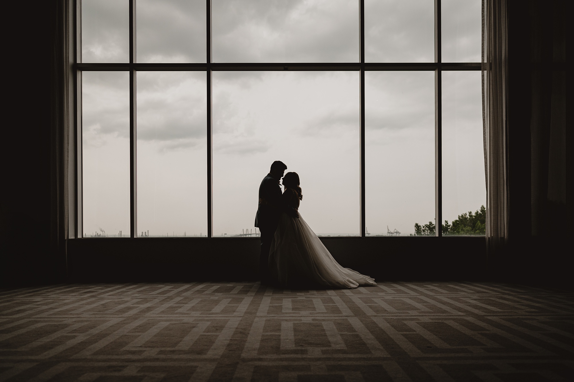 newlyweds hug in front of window at Above Staten Island