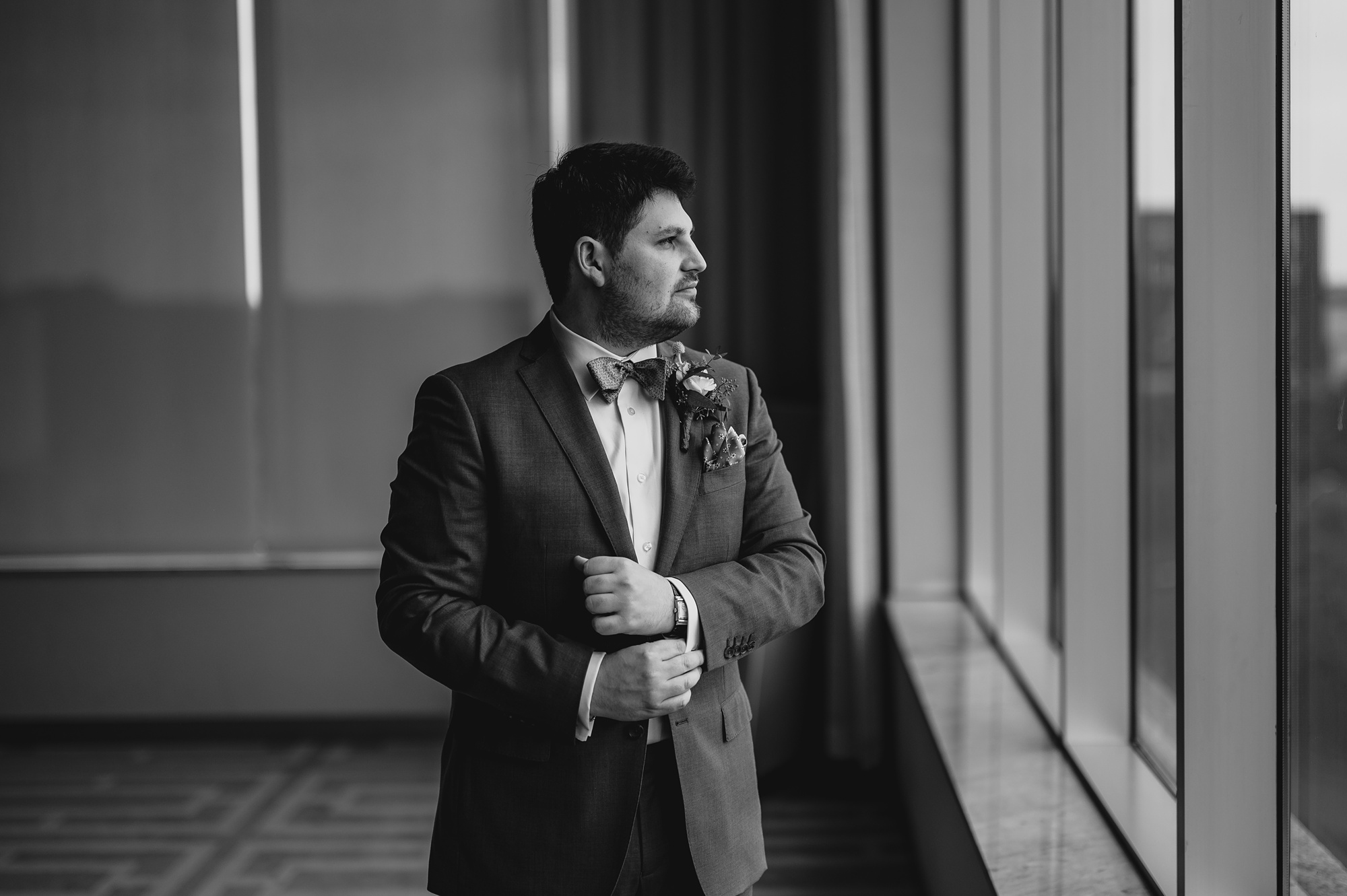 groom looks out window of wall at Above Staten Island