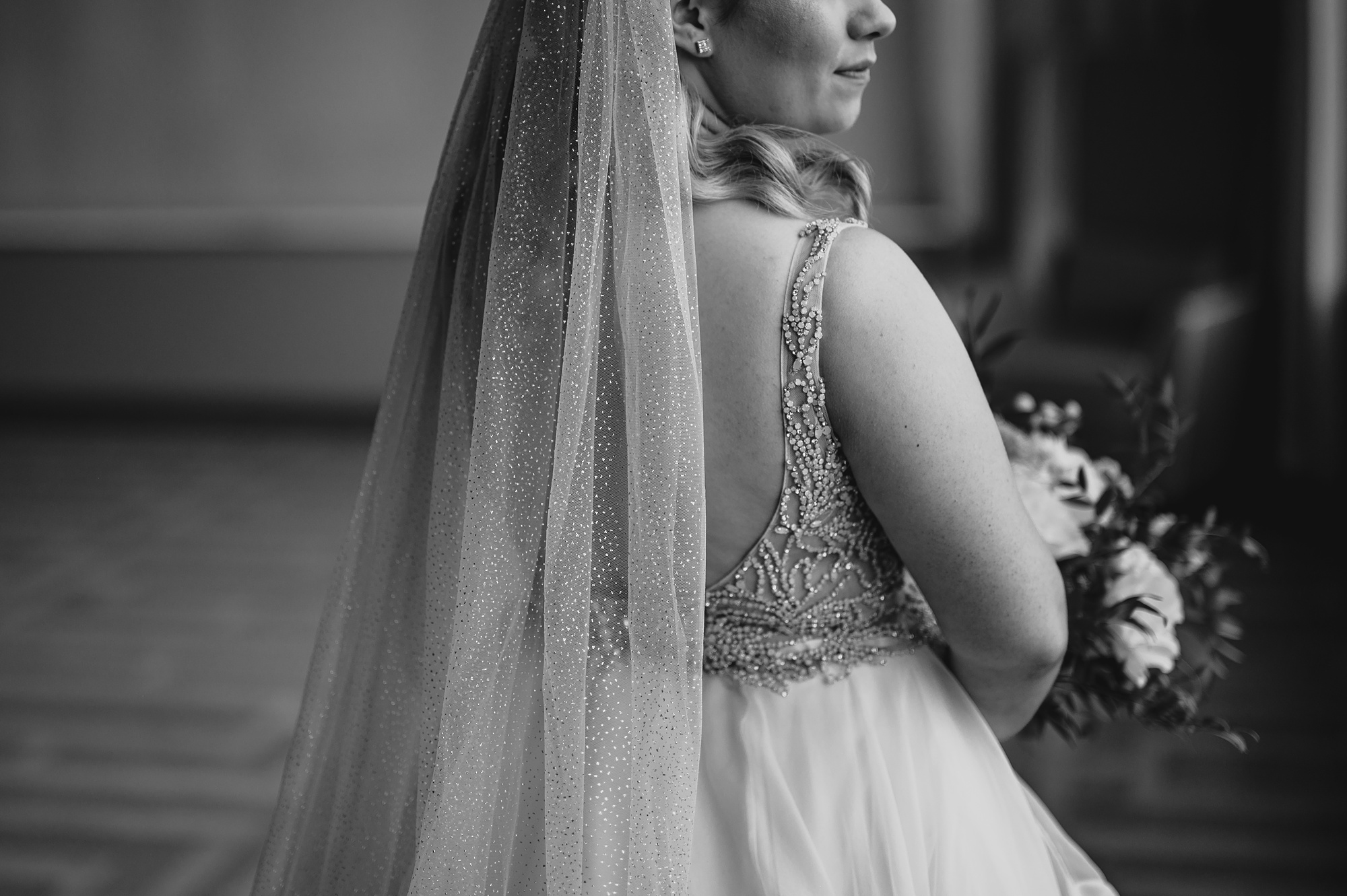 bride looks out window holding bouquet at Above Staten Island
