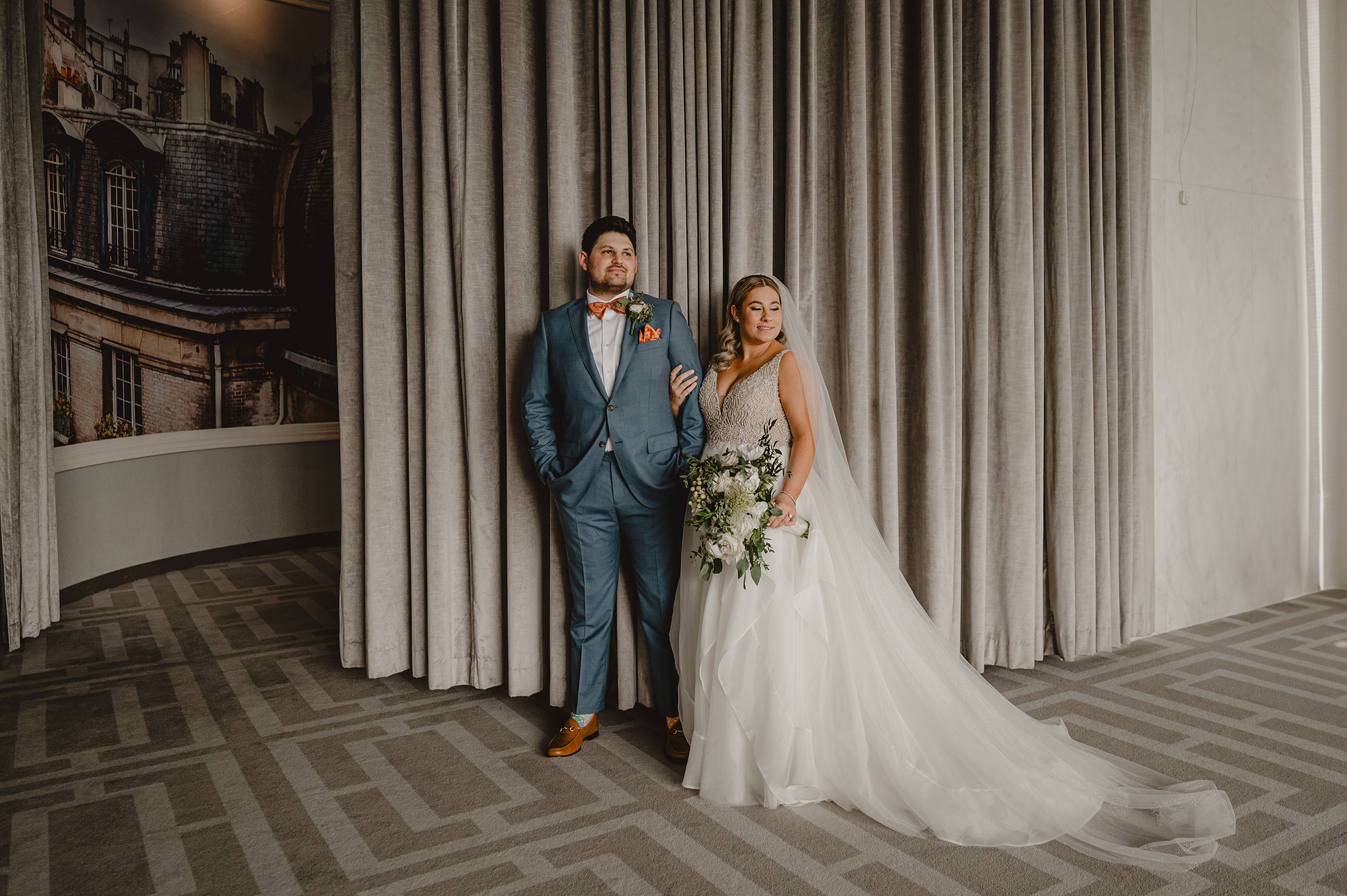 bride and groom hug in front of grey wall at Above Staten Island
