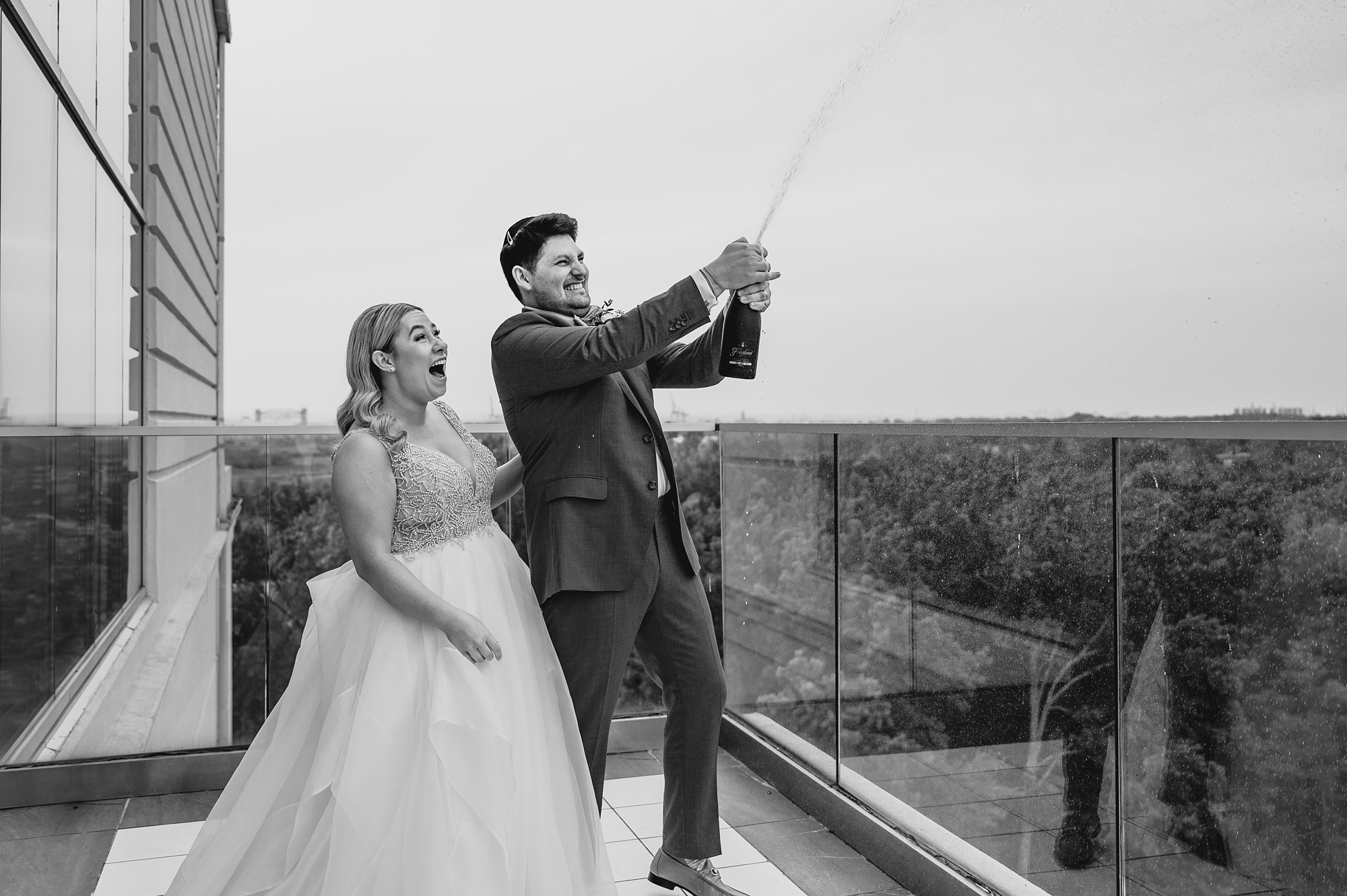 newlyweds pose champagne off rooftop patio at Above Staten Island