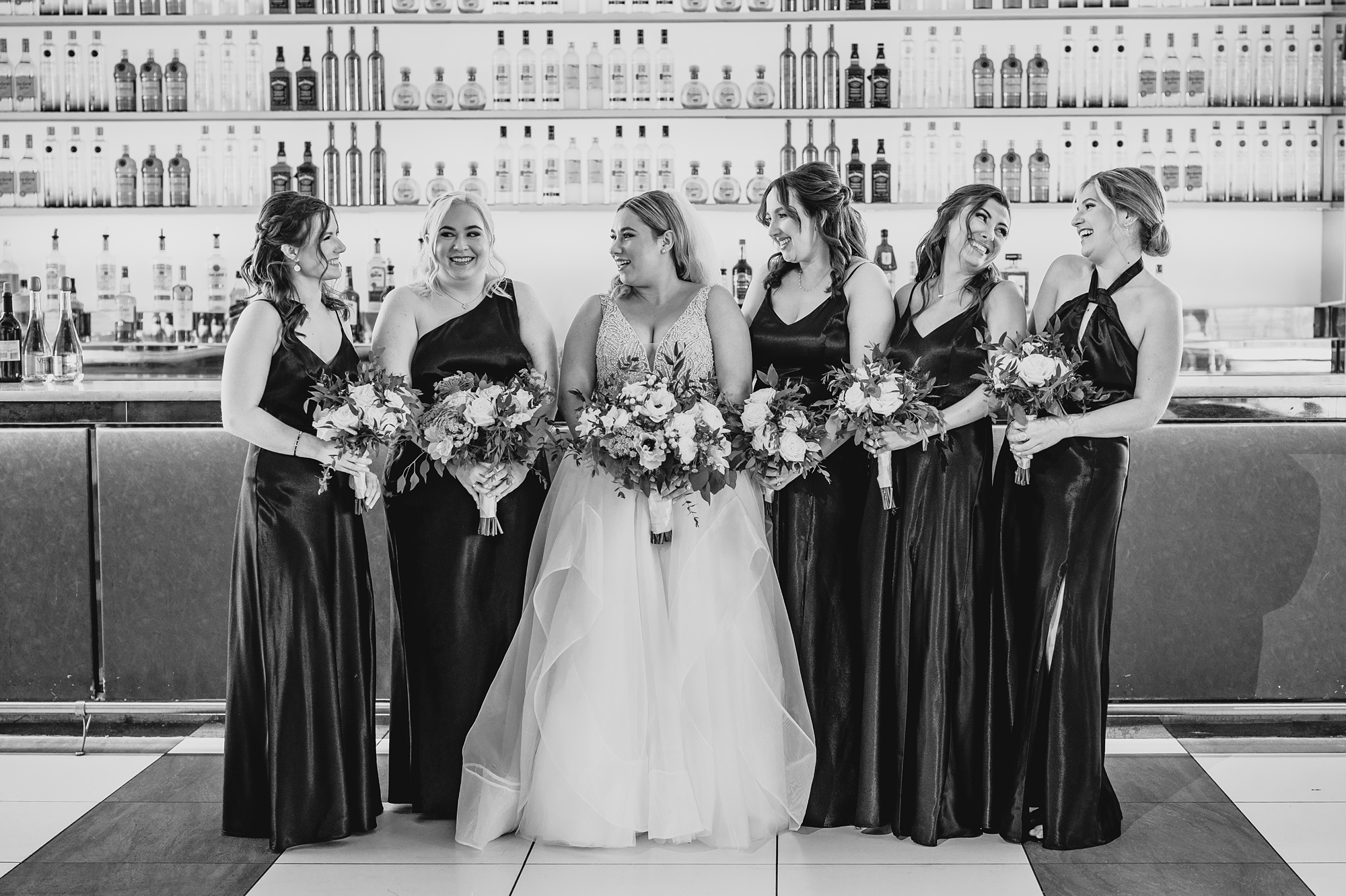 bride smiles at bridesmaids in long dresses on patio at Above Staten Island