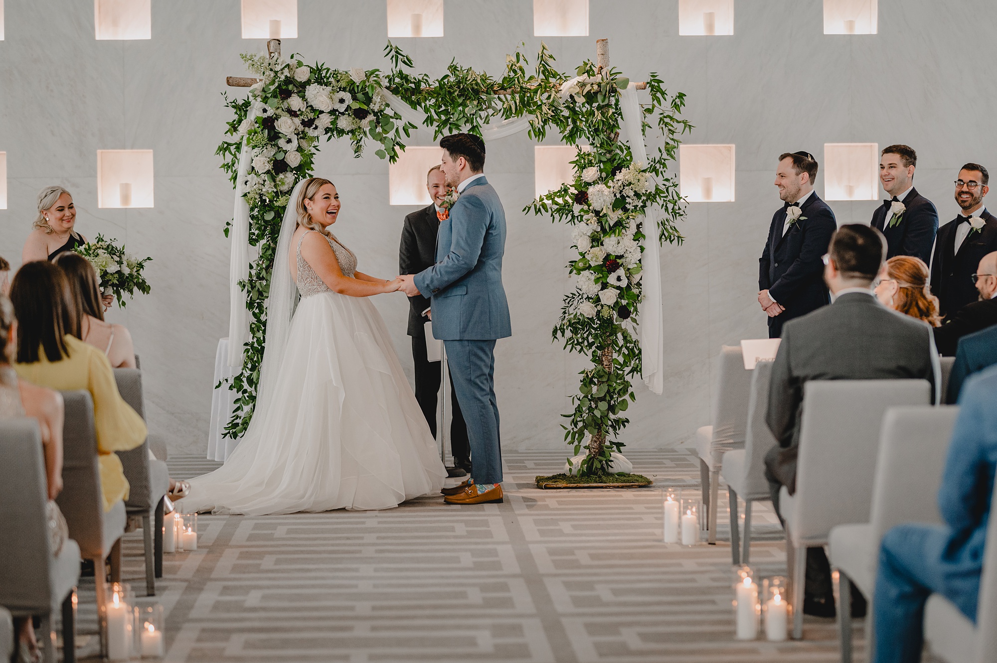 newlyweds hold hands under arbor during wedding ceremony at Above Staten Island