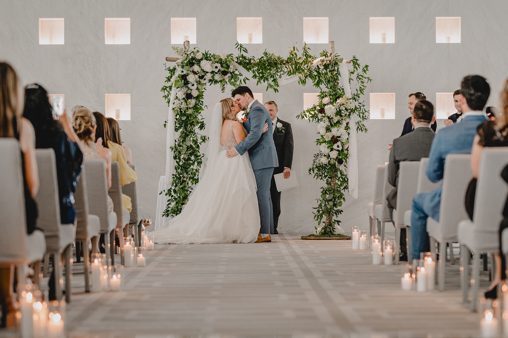 newlyweds kiss under greenery covered arbor during wedding ceremony at Above Staten Island
