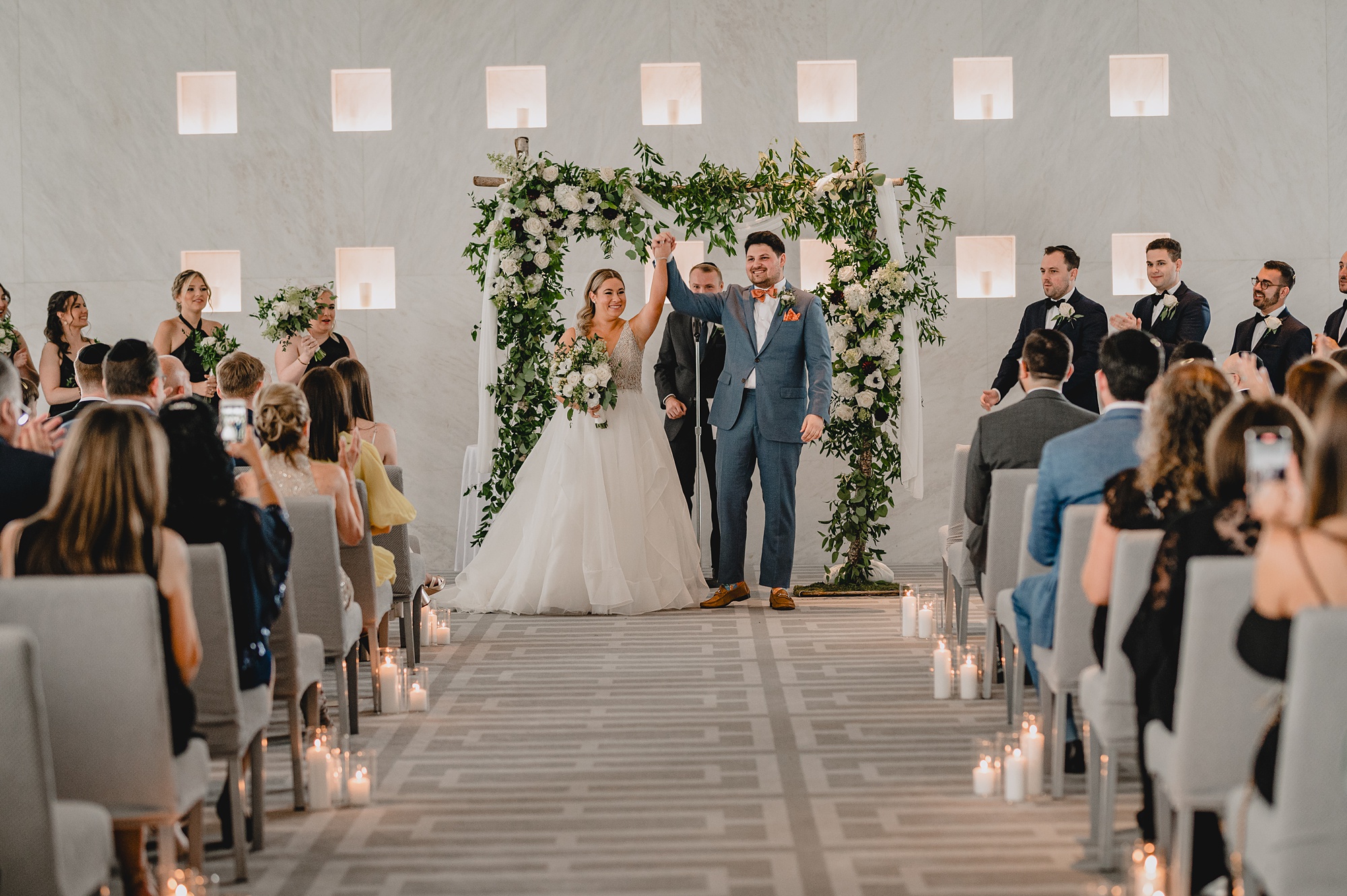 newlyweds lift hands leaving wedding ceremony at Above Staten Island