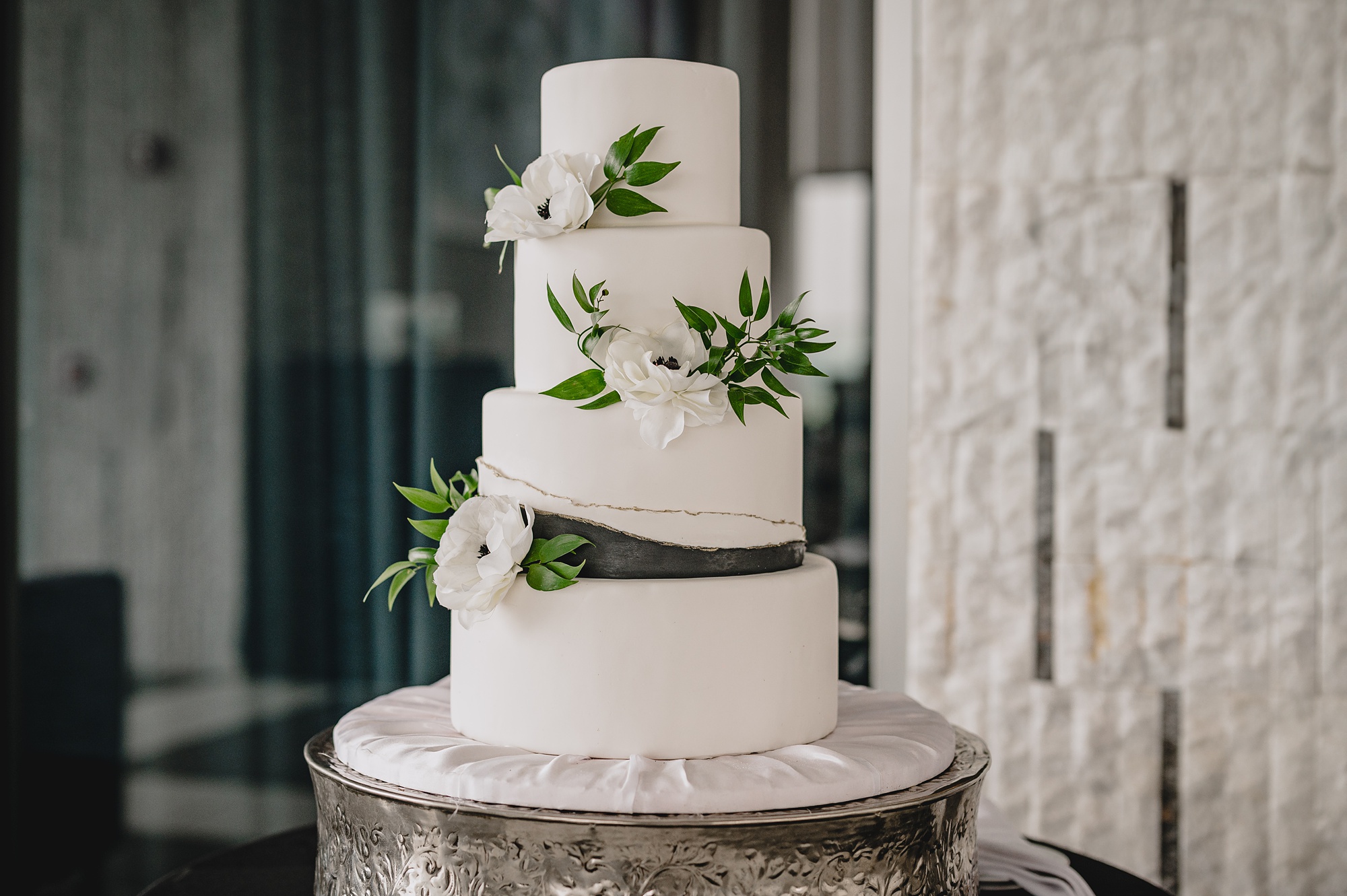 tiered wedding cake with ivory flowers and greenery