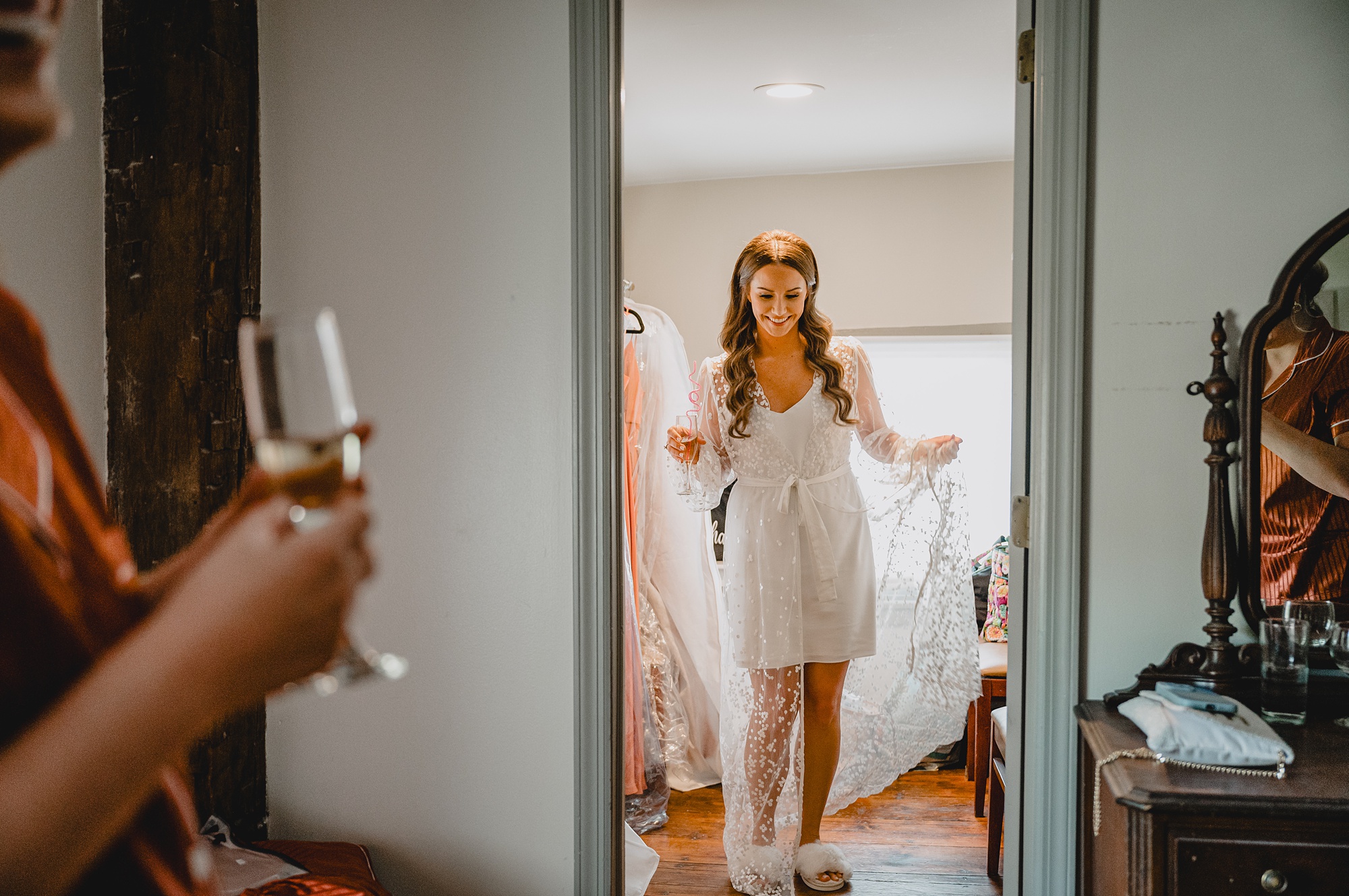 bride looks at mirror holding champagne glass