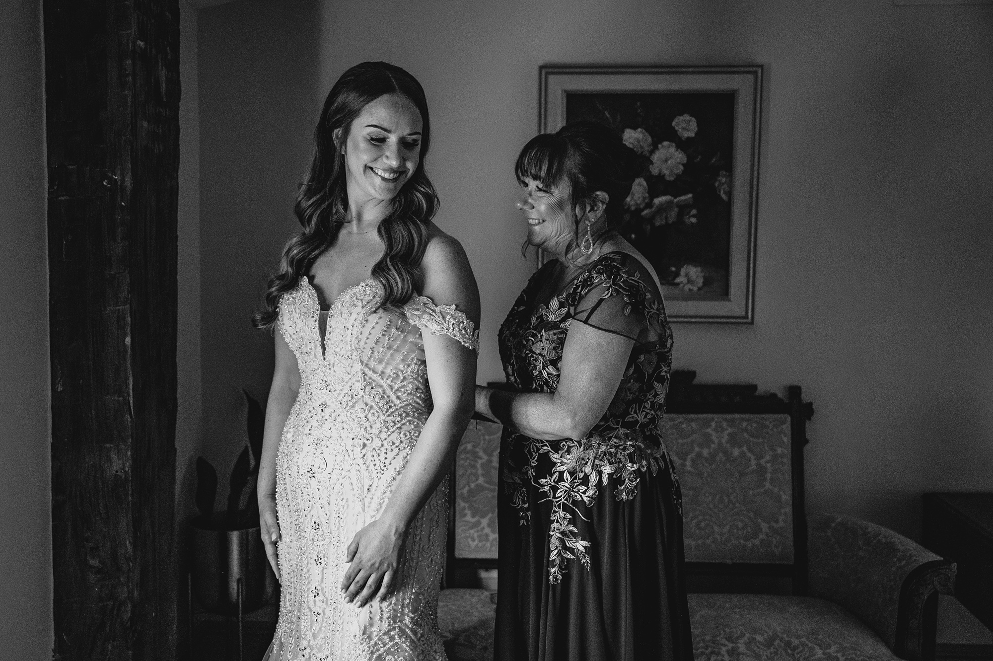 mother helps bride into wedding dress in bridal suite at David's Country Inn
