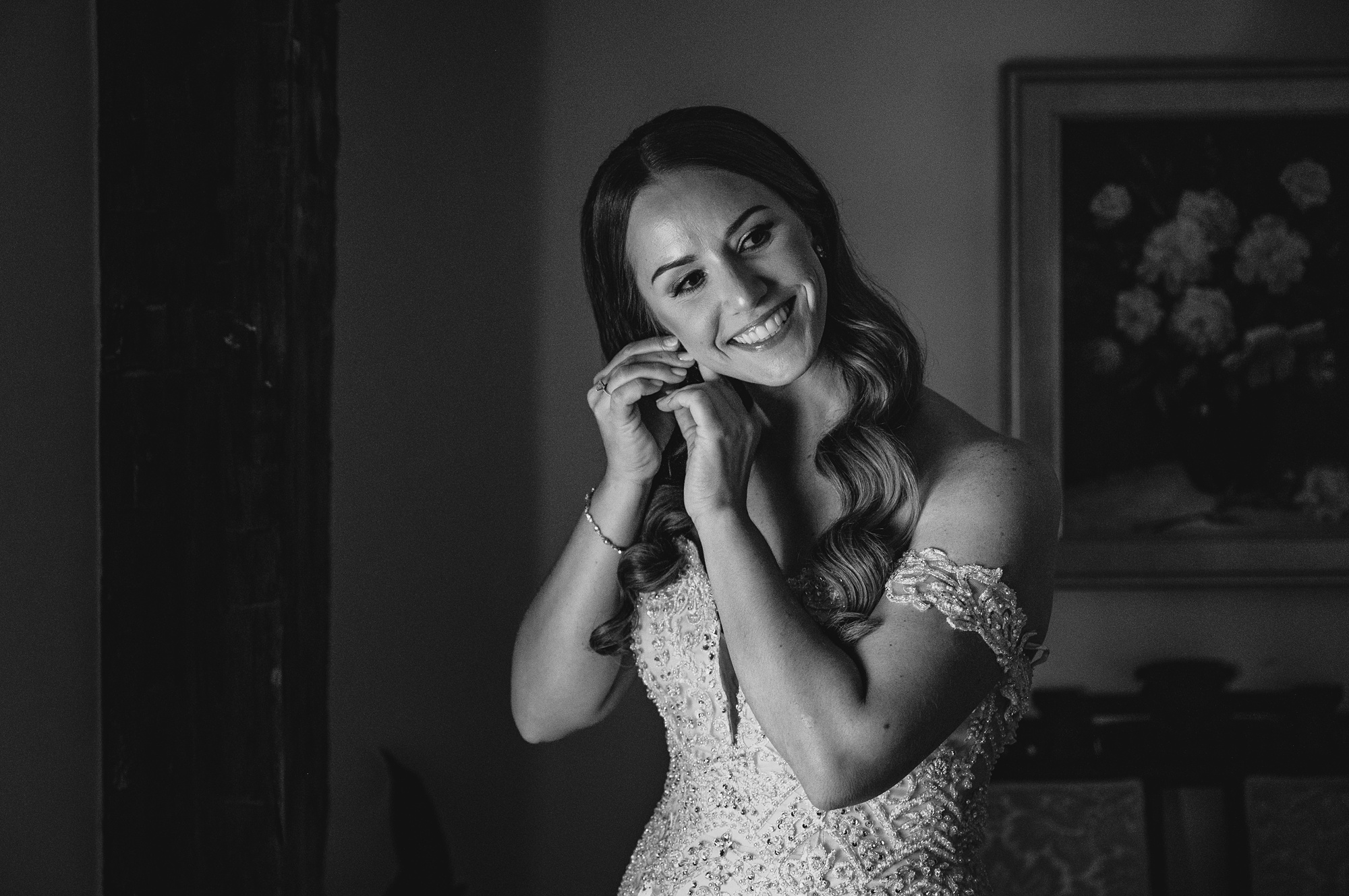 bride leans head putting on earring during prep in New Jersey