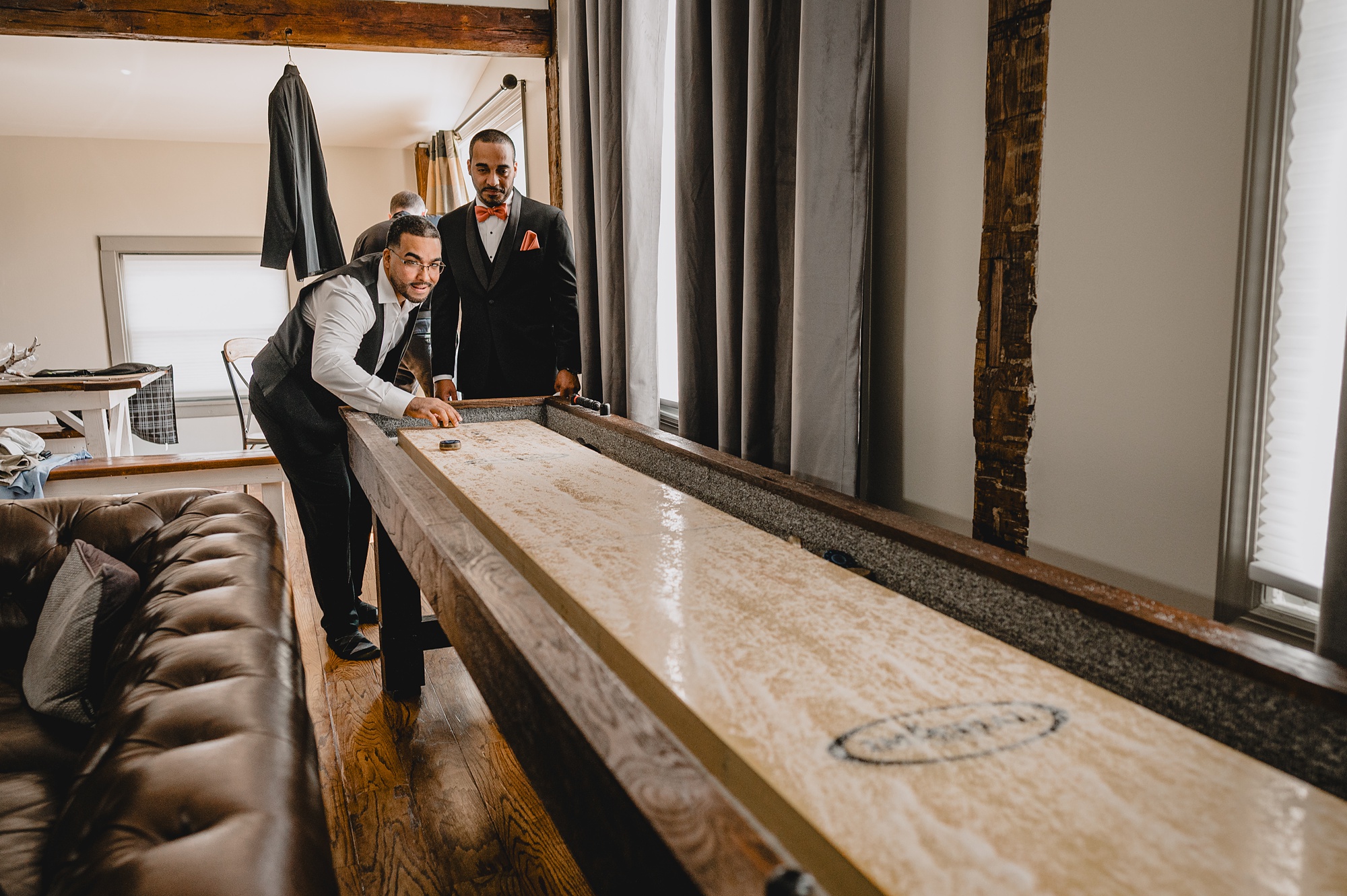 groom plays shuffleboard with groomsmen in suite at David's Country Inn