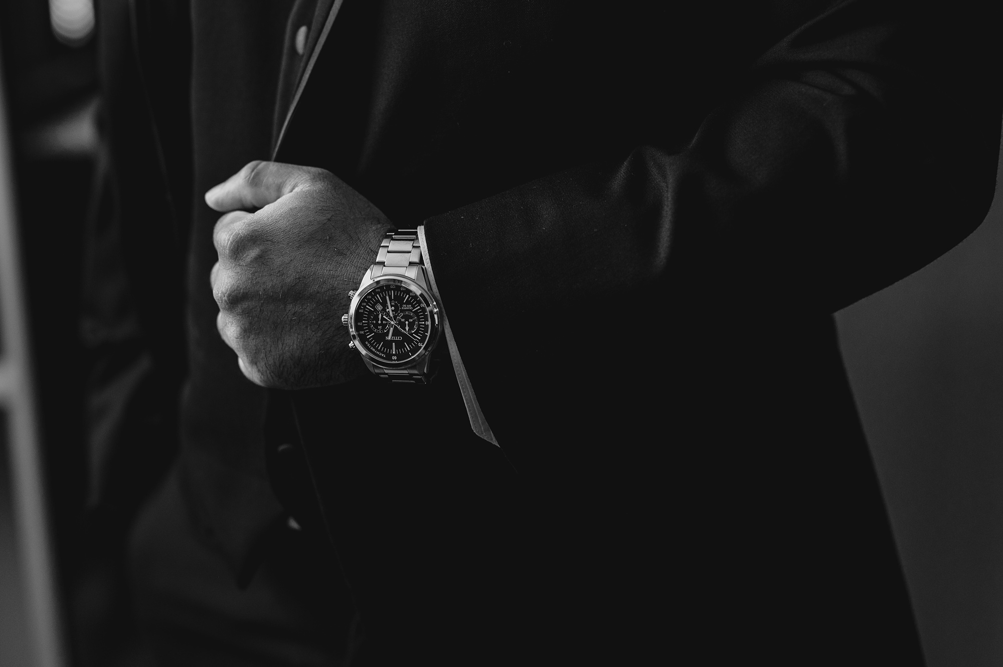 groom holds lapel jacket showing off watch