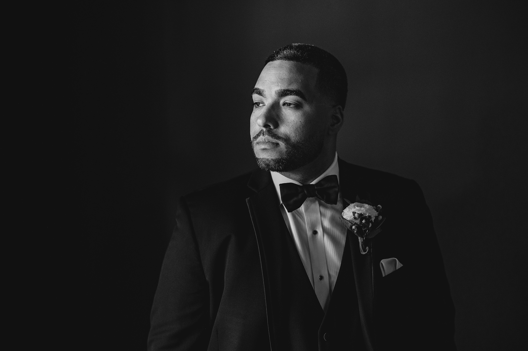 groom looks over shoulder in suit with black bowtie