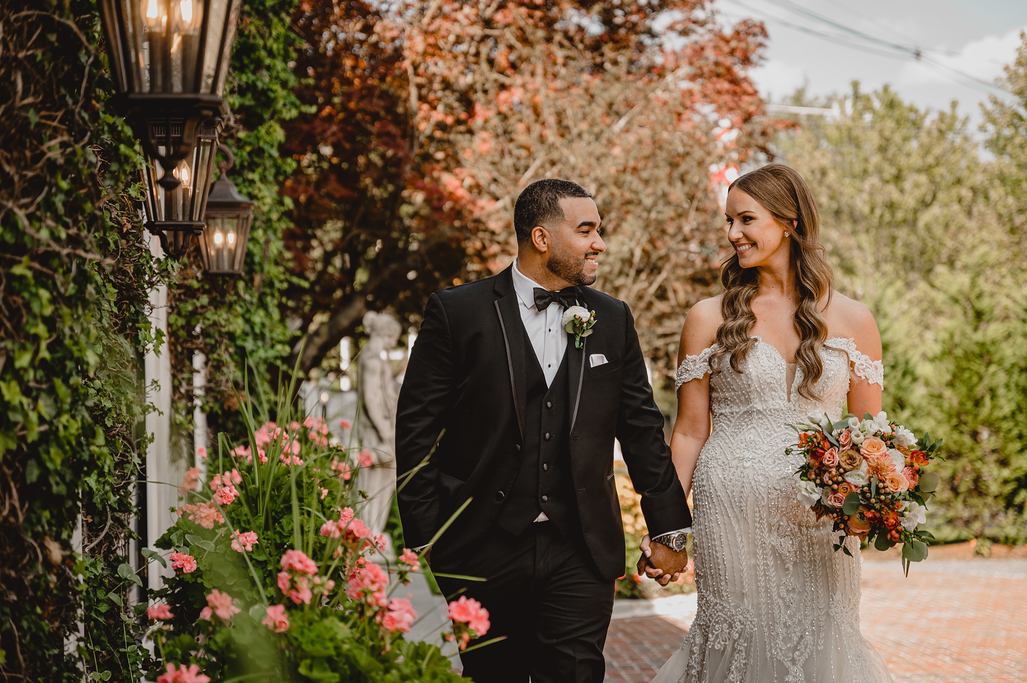 newlyweds hold hands with fall leaves around them